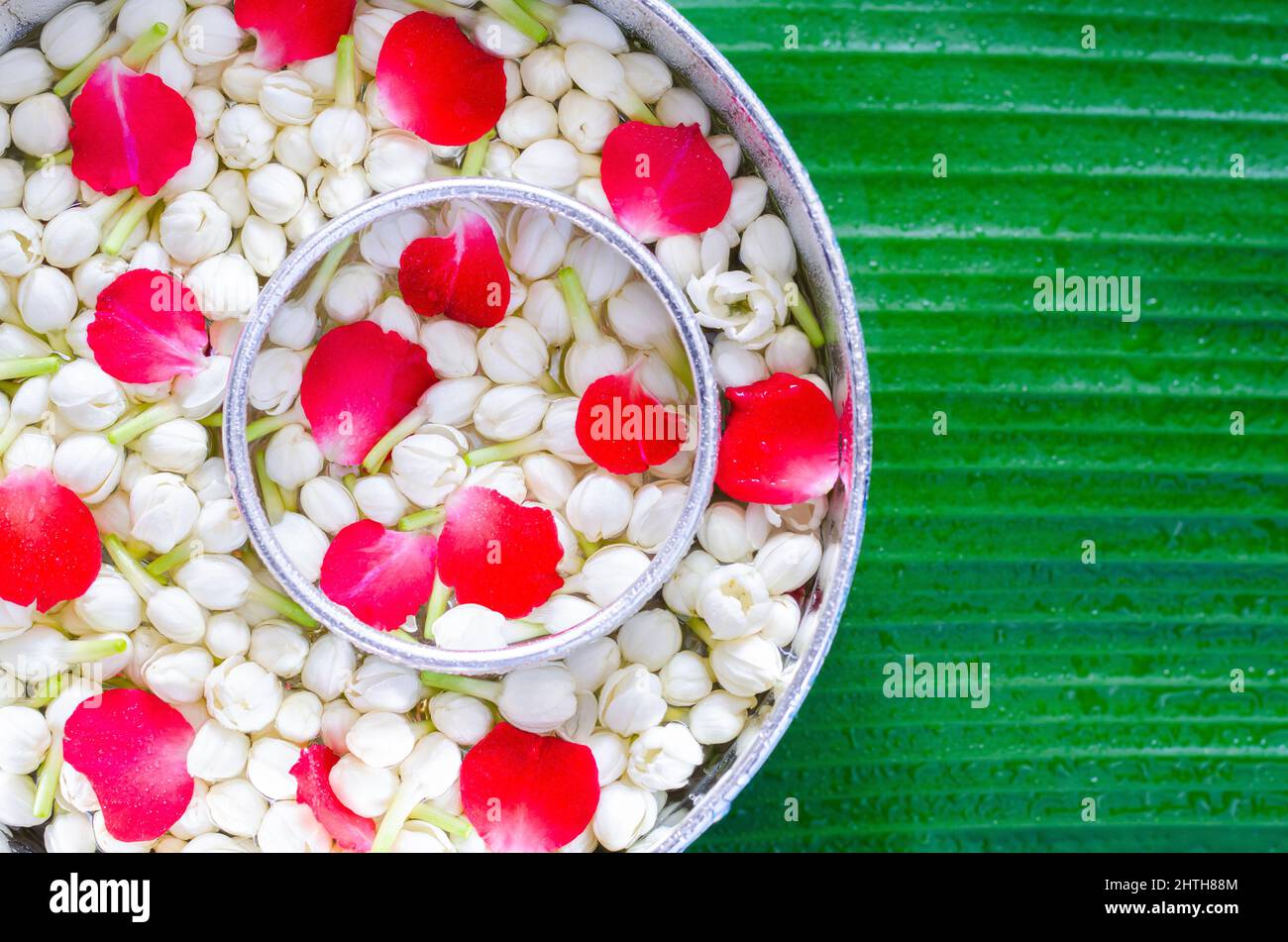 Songkran Festivalhintergrund mit Jasminblüten in Wasserschalen zum Segen auf nassem Bananenblatt Hintergrund. Stockfoto