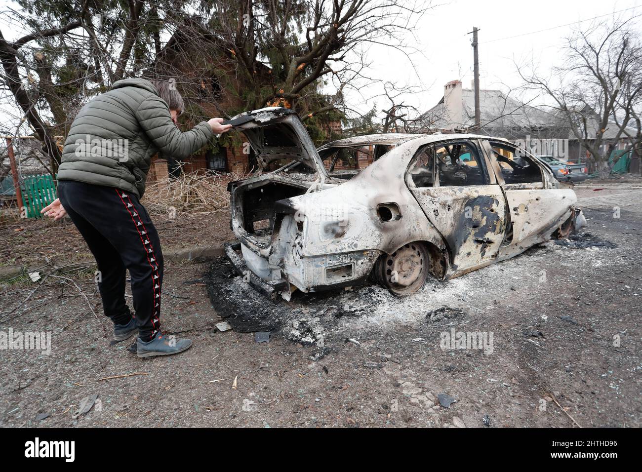 Donezk. 28.. Februar 2022. Ein Mann überprüft ein verbranntes Auto in Donezk, 28. Februar 2022. Kredit: Victor/Xinhua/Alamy Live Nachrichten Stockfoto
