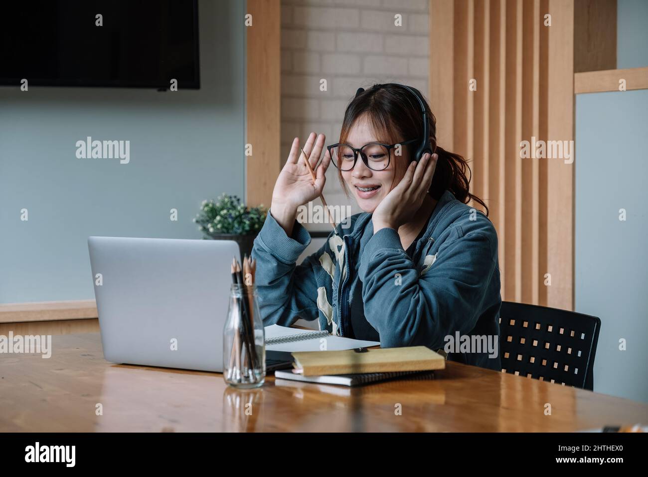Junge asiatische Studentin, die zu Hause online studiert, Laptop-Computer, Kopfhörer benutzt und Video-Chat hat. Fernarbeit, Fernunterricht. Videokonferenz Stockfoto