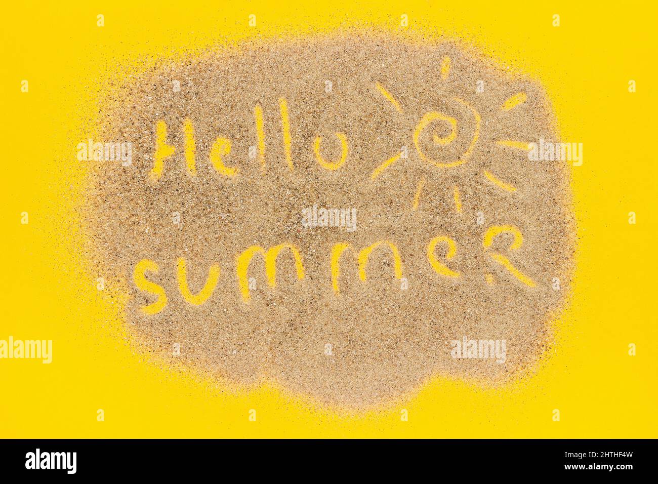 Text Hello Sommer und Sonne Zeichen auf Sand auf gelbem Papier Hintergrund gezeichnet. Kreativer Urlaub mit Top View-Konzept. Stockfoto