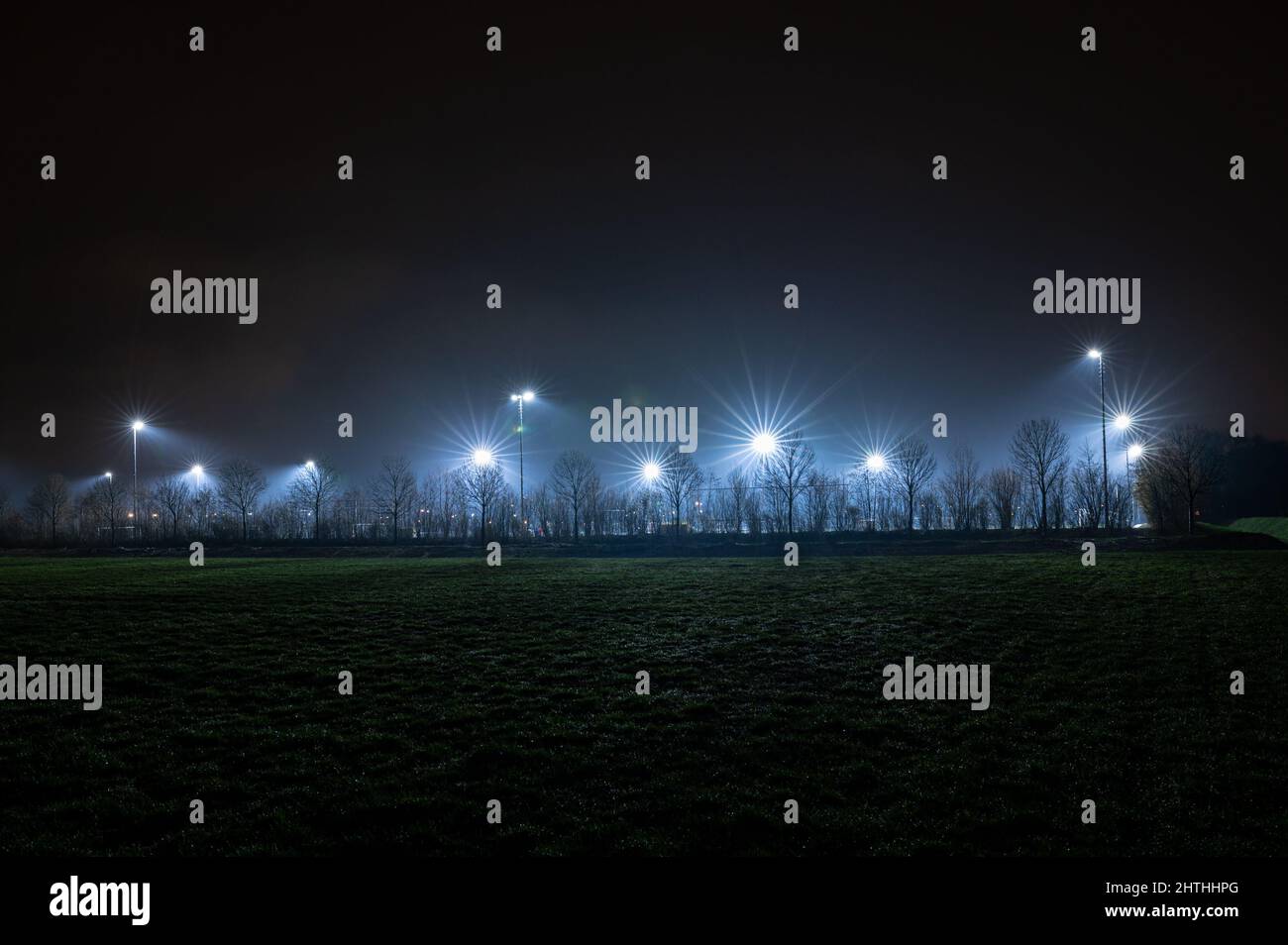 Lichtmasten beleuchten einen Sportplatz, auf dem am Abend trainiert wird Stockfoto