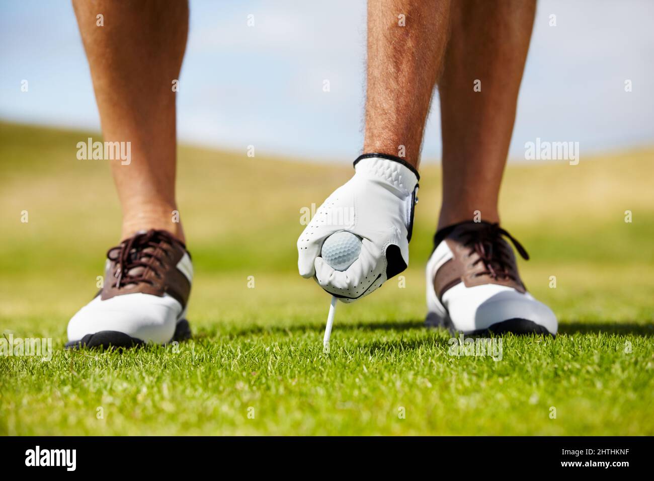 Der Anfang des Lochs. Ein Golfer, der sein T-Shirt auf dem Golfplatz in den Boden legt. Stockfoto