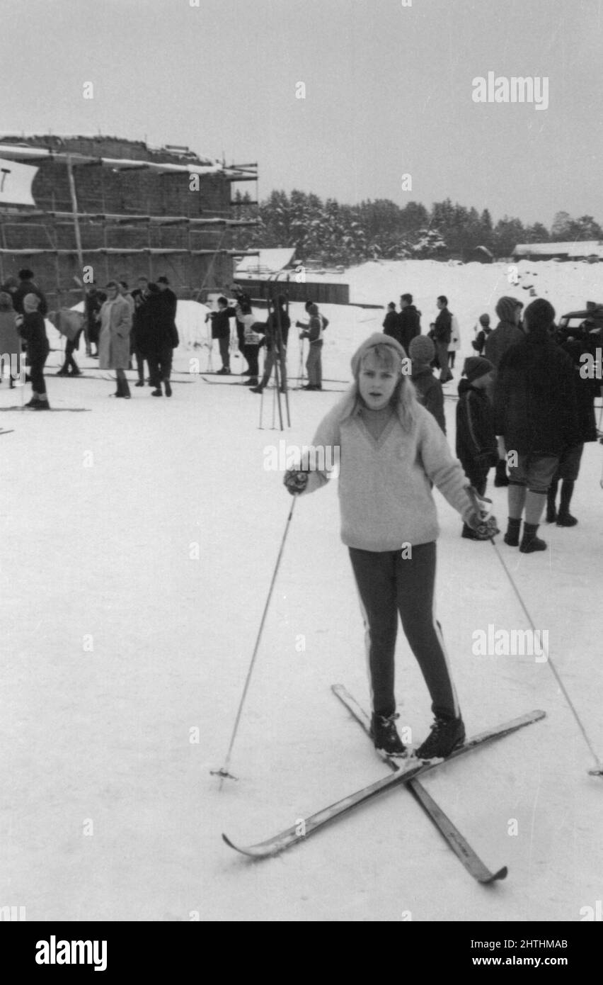 Authentisches Vintage-Foto der 1960er Jahre von einer jungen Frau auf Skiern mit Skistöcken, die die Kamera betrachten, Schweden Stockfoto