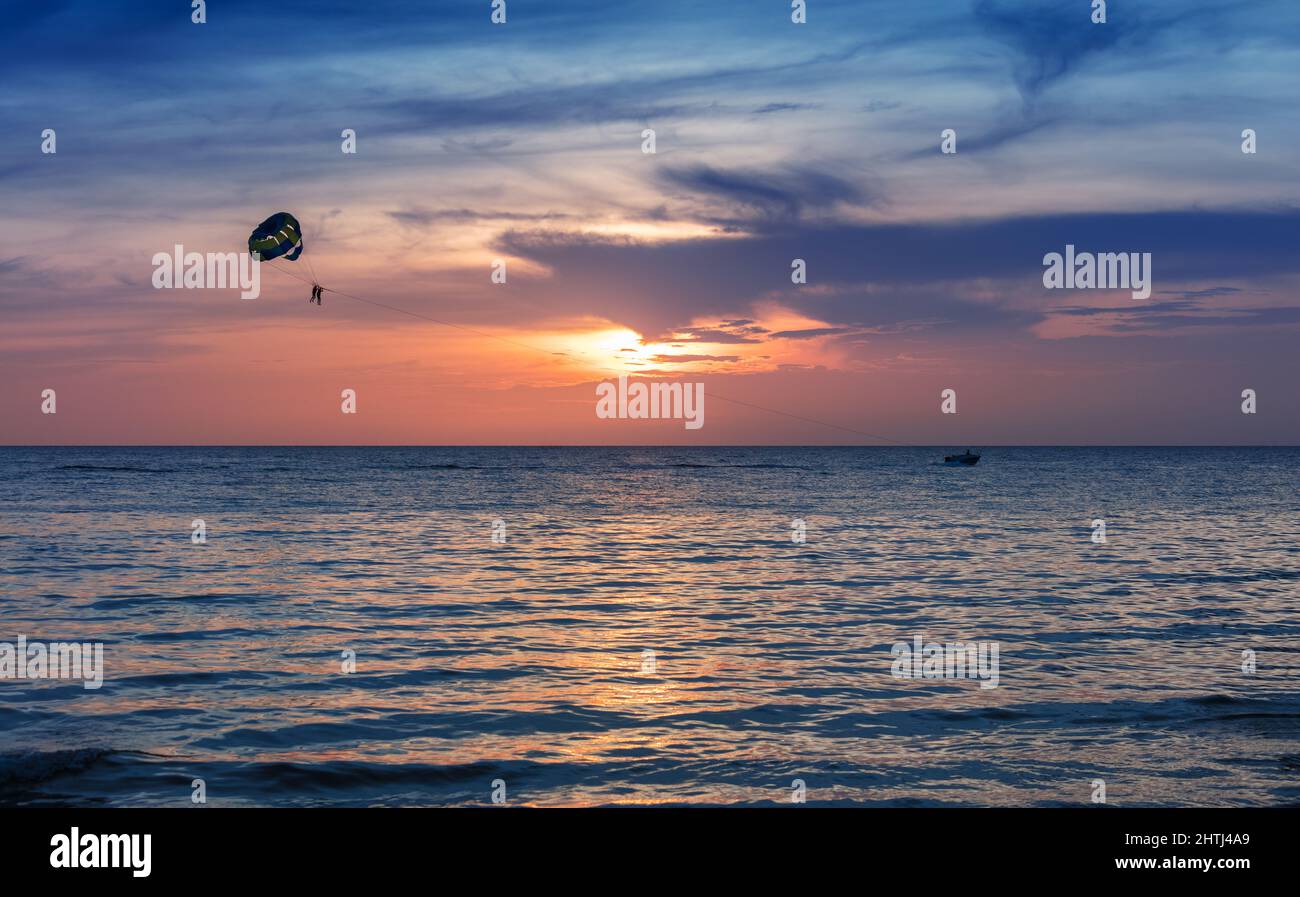 Silhouetten des Bootes mit Fallschirm in Sonnenuntergang Himmel Stockfoto