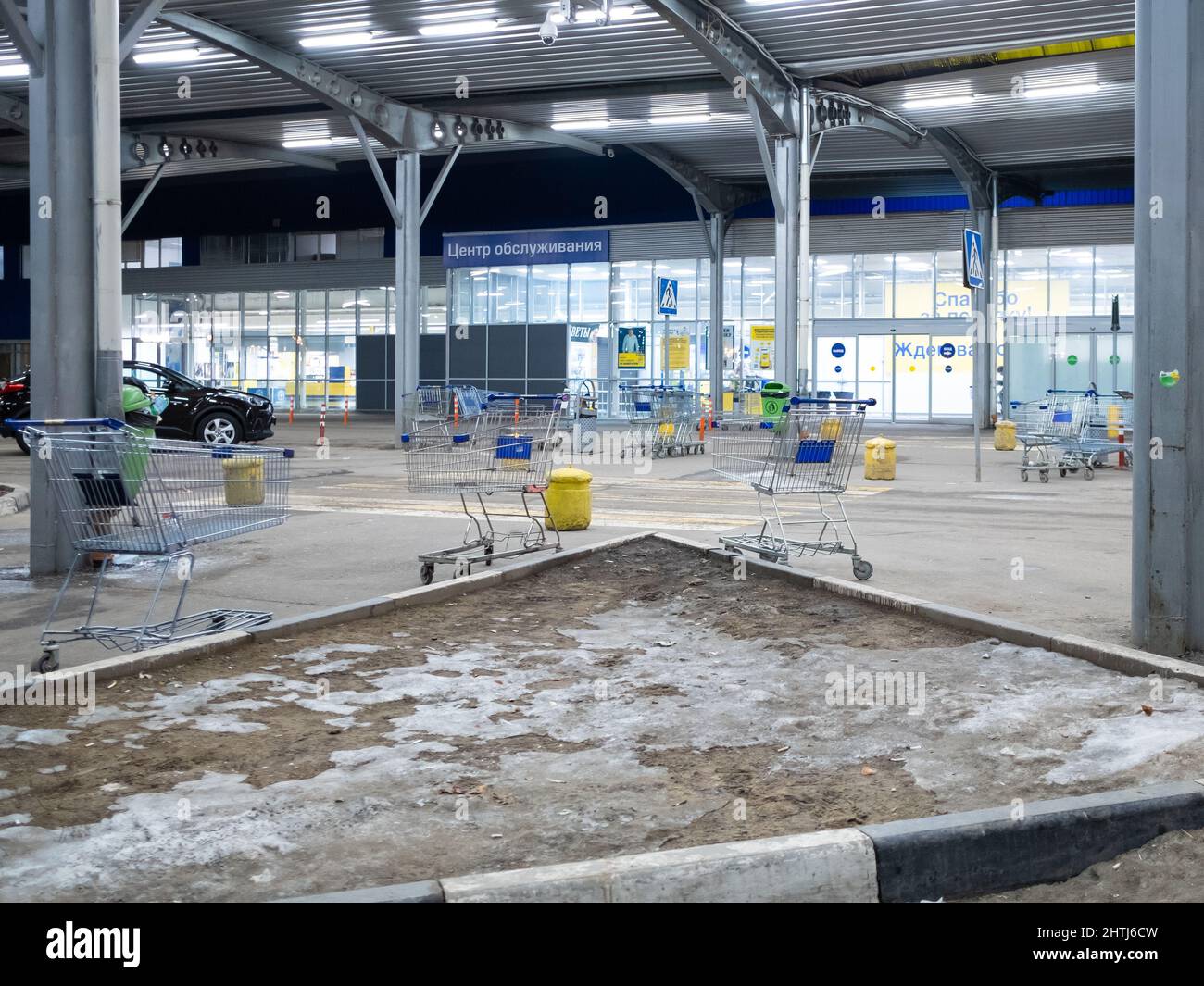Moskau. Russland. 25. Februar 2022. Zufällig platzierte Einkaufswagen auf einem halb leeren Parkplatz in der Nähe des METRO-Hypermarktes. Hell erleuchteter Parkplatz unter einem Vordach in der Nähe des METRO-Einkaufszentrums in der Nacht. Stockfoto