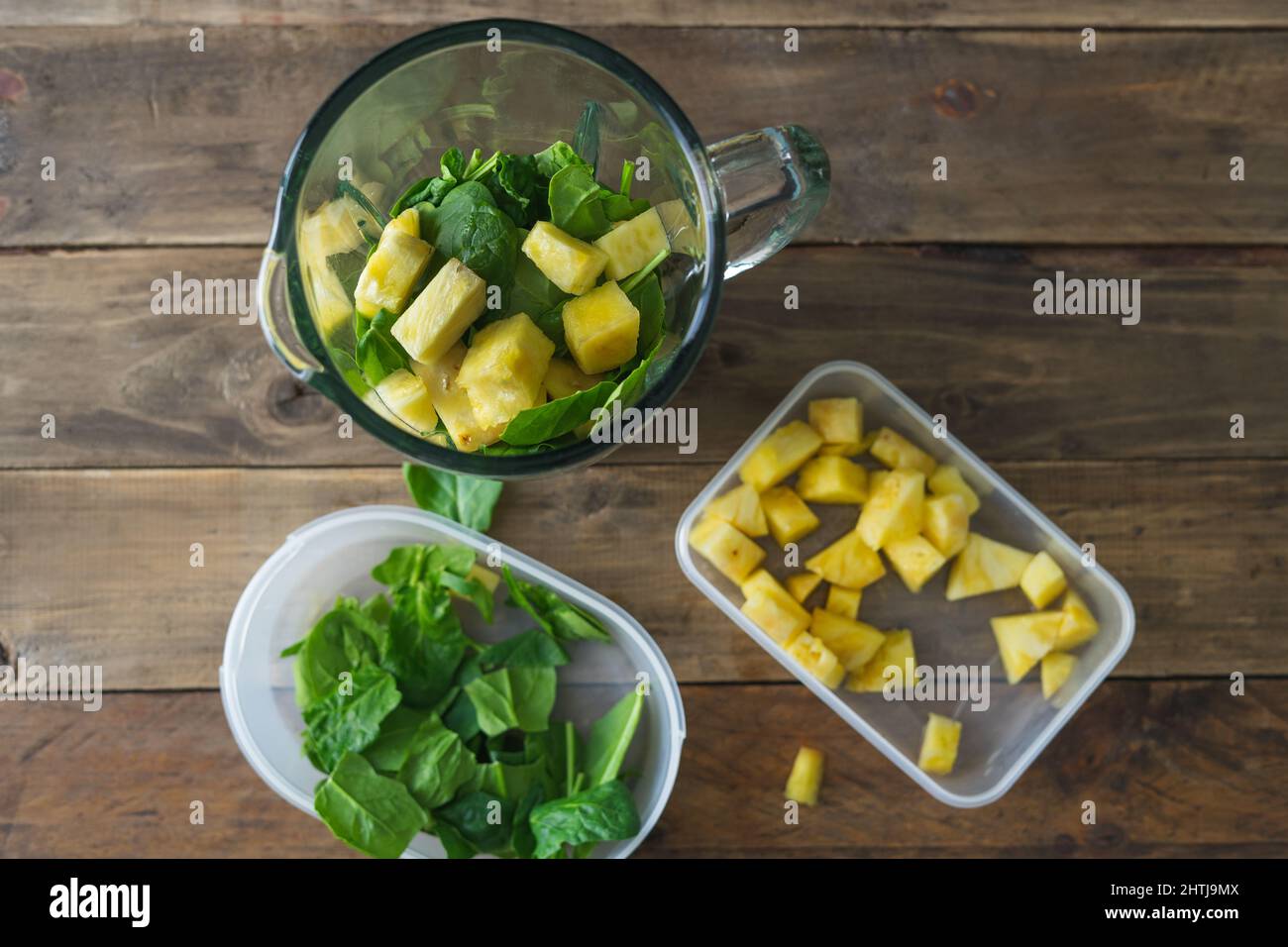 Mixglas mit Spinat und Ananas. Vorbereitung für einen gesunden Smoothie. Speicherplatz kopieren. Holzboden. Draufsicht. Stockfoto