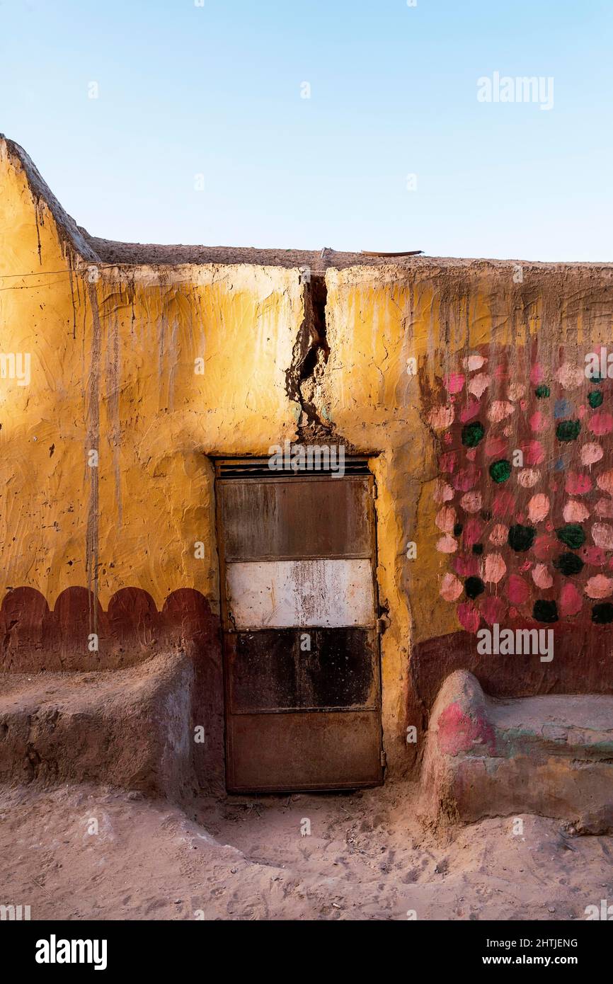 Rissige schäbige Wand des alten Gebäudes mit bunt bemalten Geröllchen und verwitterte Tür auf der Straße der Stadt Ägypten Stockfoto