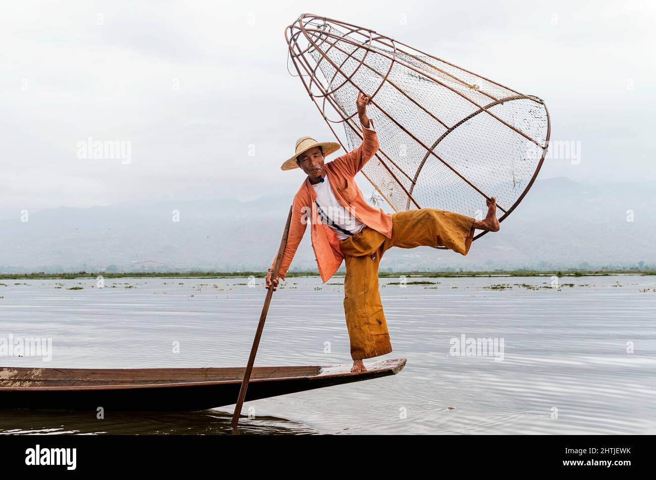 Shan Provinz, Myanmar - 04.18.2017: Ganzer Körper von asiatischen lokalen Fischern mit traditioneller Fangausrüstung, die auf dem Boot steht, während sie auf Inle Lak Fische fangen Stockfoto