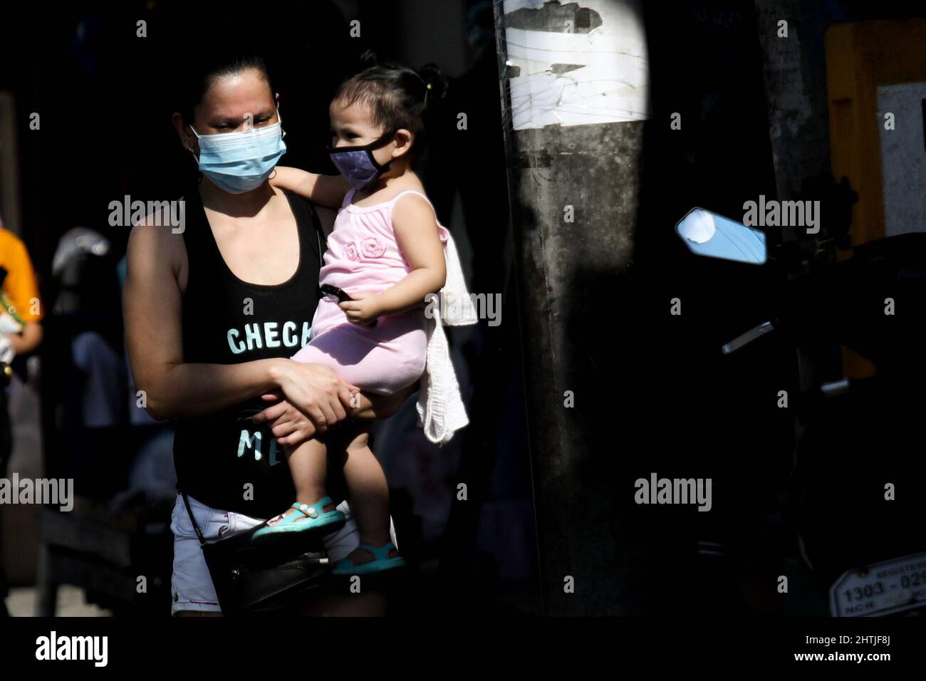 Manila, Philippinen. 1. März 2022. Eine Mutter trägt ihr Kind, während sie eine Straße in Quezon City, Philippinen, entlang gehen. 1. März 2022. Die philippinische Regierung hat am 1. März die COVID-19-Beschränkungen in Metro Manila gelockert, was es Einrichtungen und öffentlichen Verkehrsmitteln ermöglicht, mit dem Sinken der Coronavirus-Fälle voll ausgelastet zu sein. (Bild: © Basilio Sepe/ZUMA Press Wire) Stockfoto