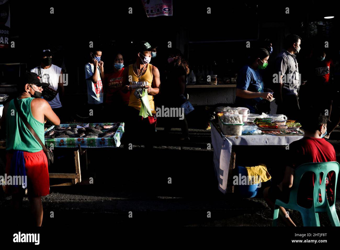 Manila, Philippinen. 1. März 2022. Menschen mit Schutzmasken kaufen Lebensmittel entlang einer Straße in Quezon City, Philippinen. 1. März 2022. Die philippinische Regierung hat am 1. März die COVID-19-Beschränkungen in Metro Manila gelockert, was es Einrichtungen und öffentlichen Verkehrsmitteln ermöglicht, mit dem Sinken der Coronavirus-Fälle voll ausgelastet zu sein. (Bild: © Basilio Sepe/ZUMA Press Wire) Stockfoto