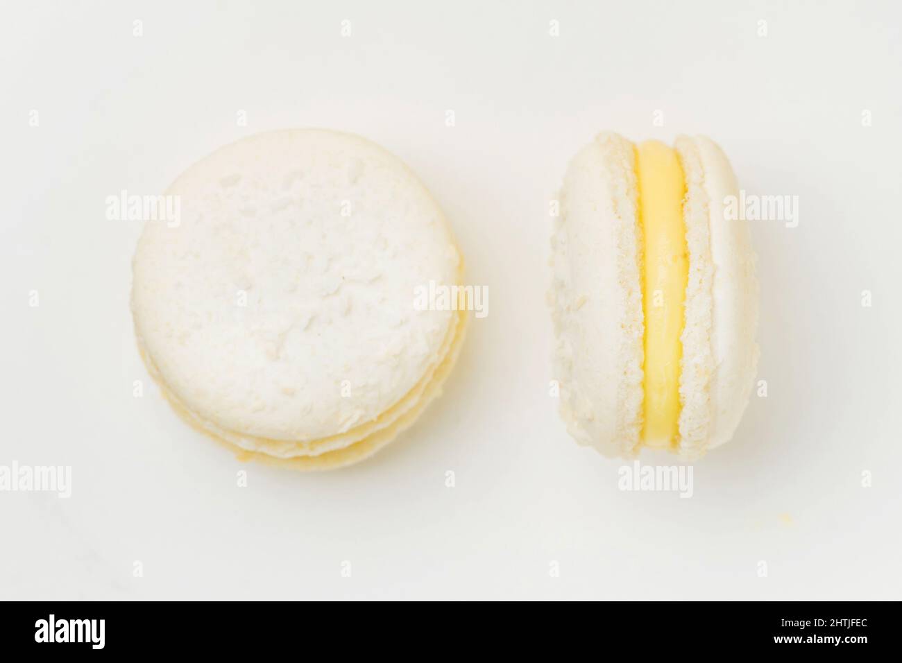 Draufsicht auf leckere runde Makronen mit Vanillegeschmack und süßgelber Füllung auf weißem Hintergrund im hellen Raum Stockfoto