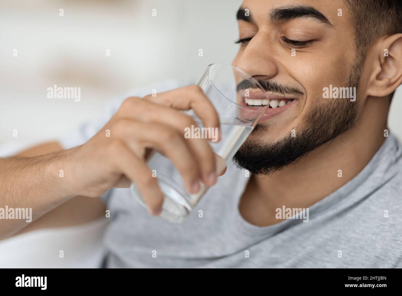 Porträt Eines Hübschen Jungen Arabischen Mannes, Der Wasser Aus Glas Trinkt Stockfoto