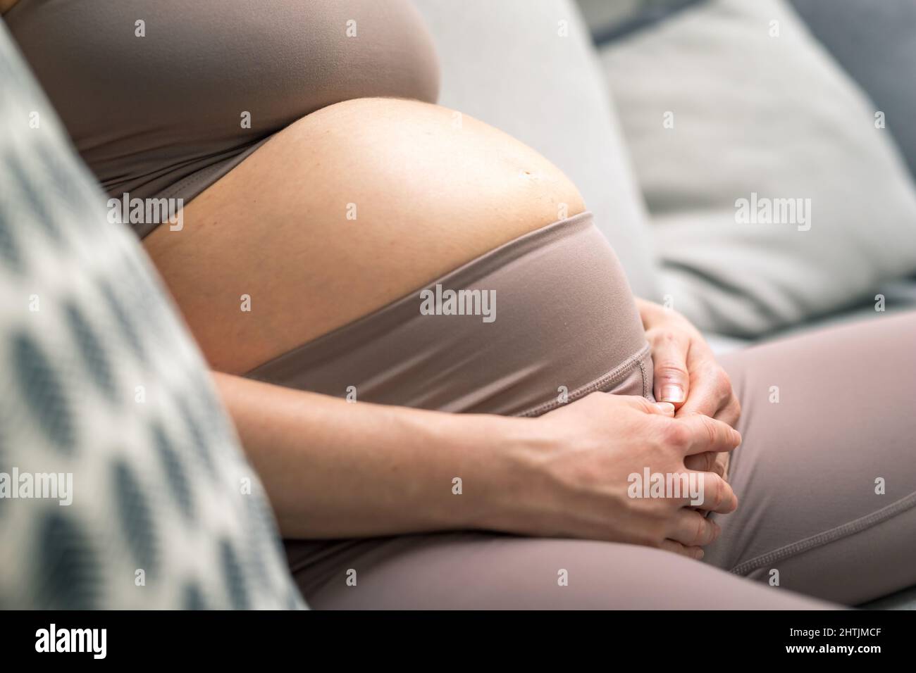 Bauch einer Schwangeren. Schwangerschaftskonzept. Schwanger Bauch Nahaufnahme. Detail der Schwangeren, die sich zu Hause auf dem bequemen Sofa entspannen. Stockfoto