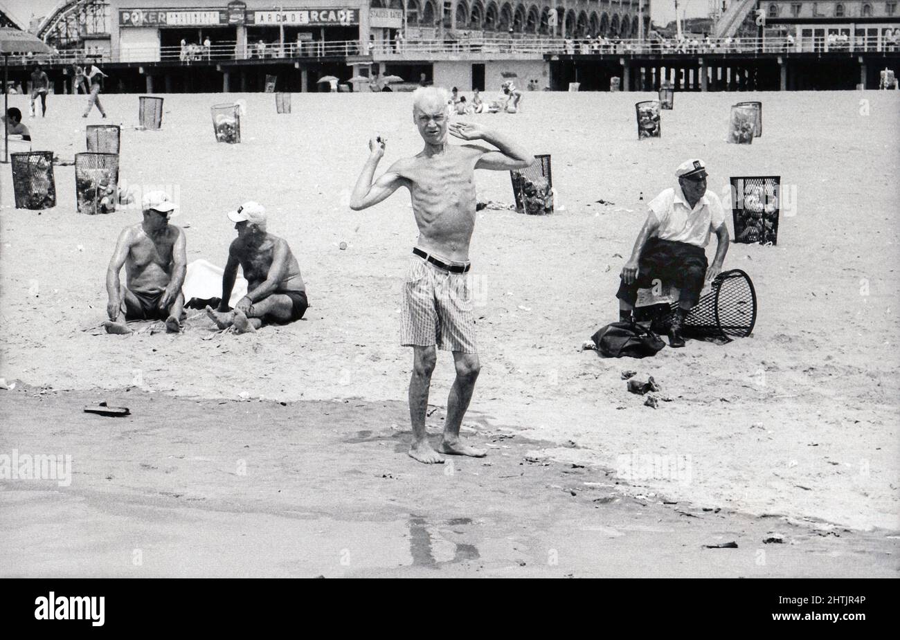 4 Senioren am Meeresrand, darunter einer, der sehr dünn ist. In Coney Island, Brooklyn, New York um 1975. Stockfoto