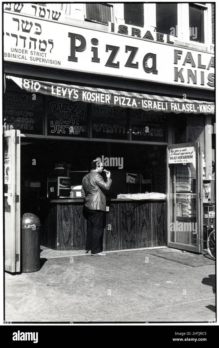 Ein orthodoxer jüdischer Mann mit einer Totenkopfkappe isst koschere Pizza im Levy's auf der 13. Avenue im Borough Park, Brooklyn, New York City. Der Boro Park ist ein orthodoxes jüdisches Viertel. Ca. 1978. Stockfoto
