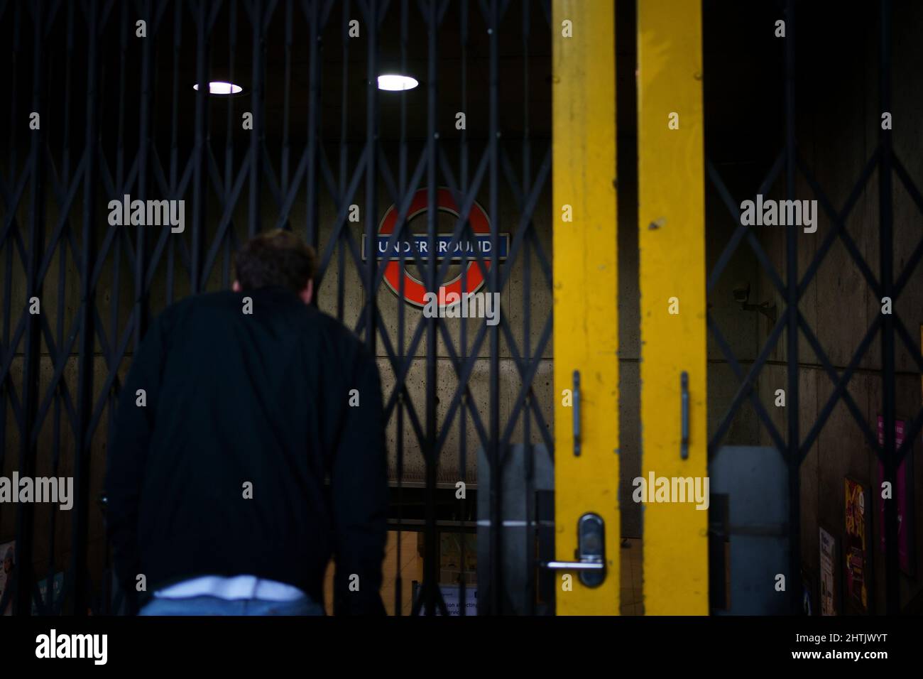 Ein Mann quiegt durch Metallstangen am Eingang der Westminster-U-Bahnstation, da alle Londoner U-Bahnlinien während eines Streiks von Mitgliedern der GMT ausgesetzt werden. Bilddatum: Dienstag, 1. März 2022. Stockfoto