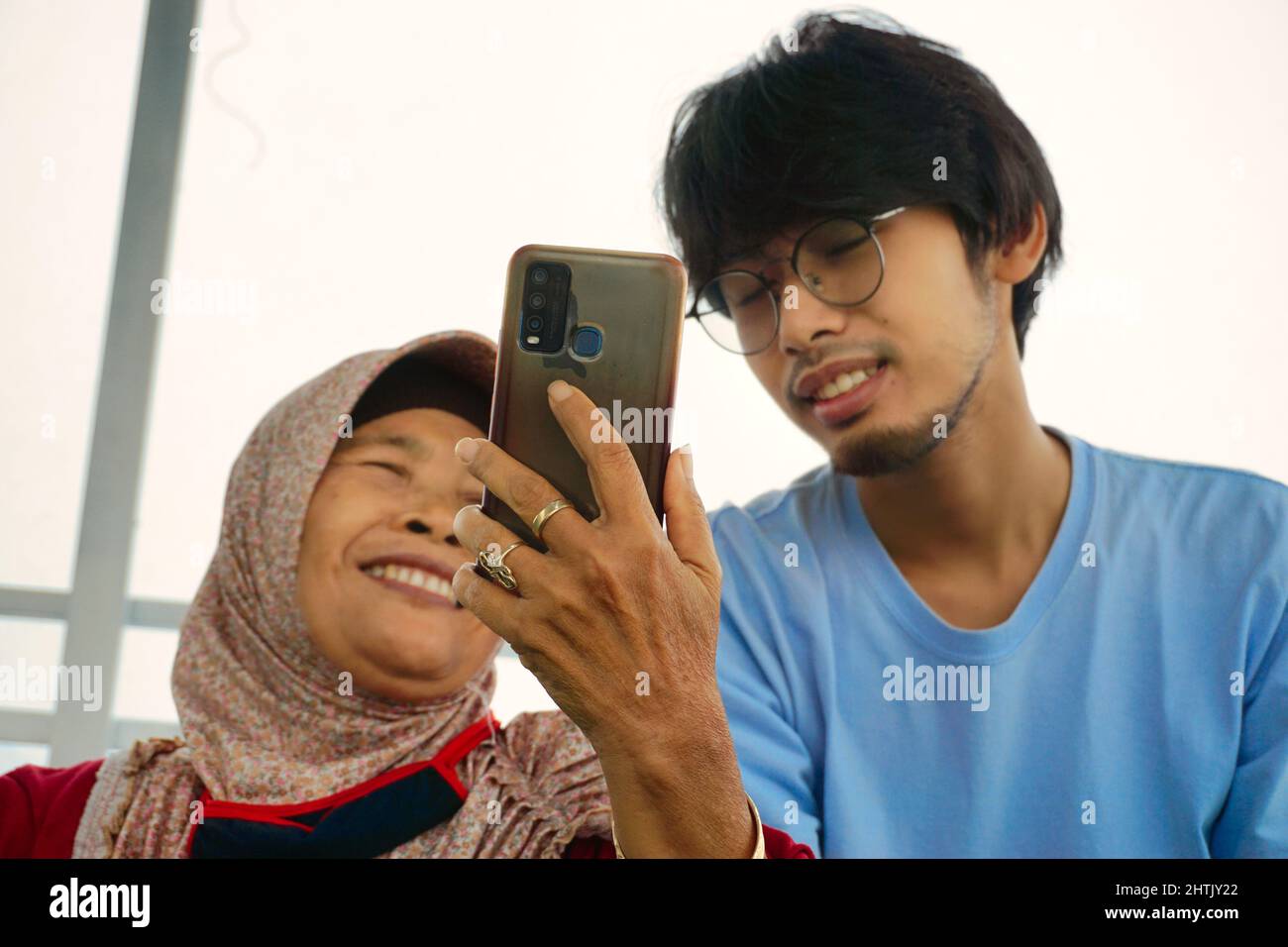 Mutter und Sohn kommunizieren über das Smartphone mit ihrer Familie von zu Hause aus Stockfoto