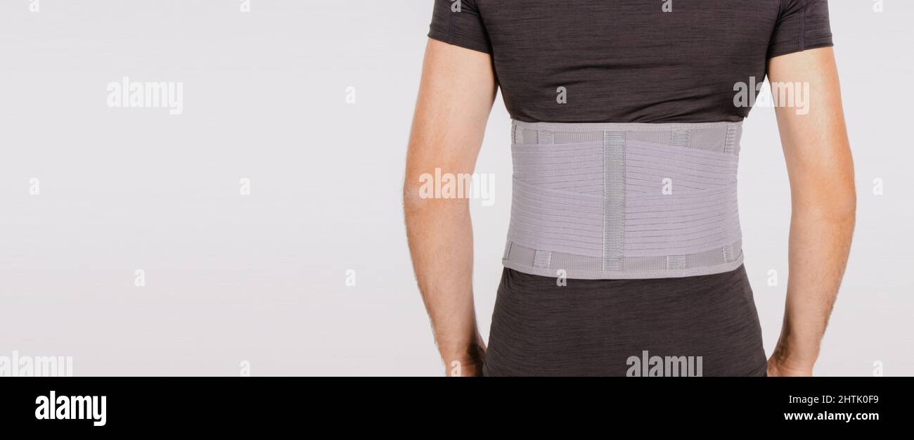 Lendenwirbelstütze am menschlichen Körper isoliert auf weißem Hintergrund. Trauma des Rückens. Rückenstütze, orthopädische Lendenwirbelstütze, Stützgurt für die Rückenmuskulatur. Senken Stockfoto