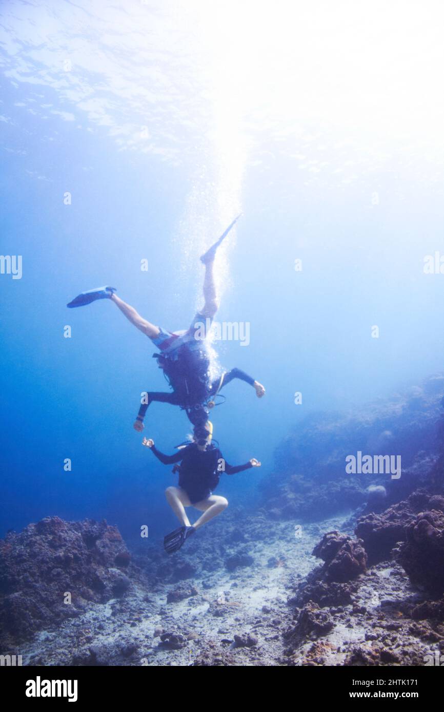 Unterwasserabenteuer. Zwei schwimmende Taucher, die Kopf an Kopf und auf dem Kopf unter Wasser herumtörneln - Copyspace. Stockfoto