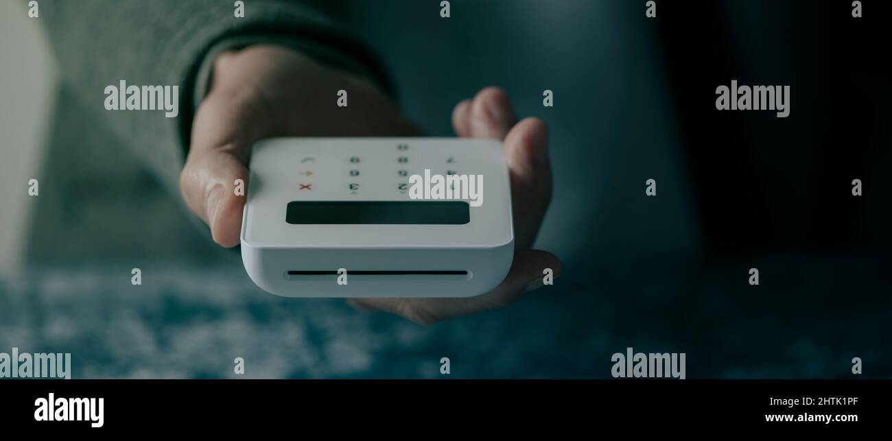 Nahaufnahme eines kaukasischen Mannes mit einem drahtlosen Zahlungsterminal in der Hand, in einem Panoramaformat, das als Webbanner oder Header verwendet werden kann Stockfoto