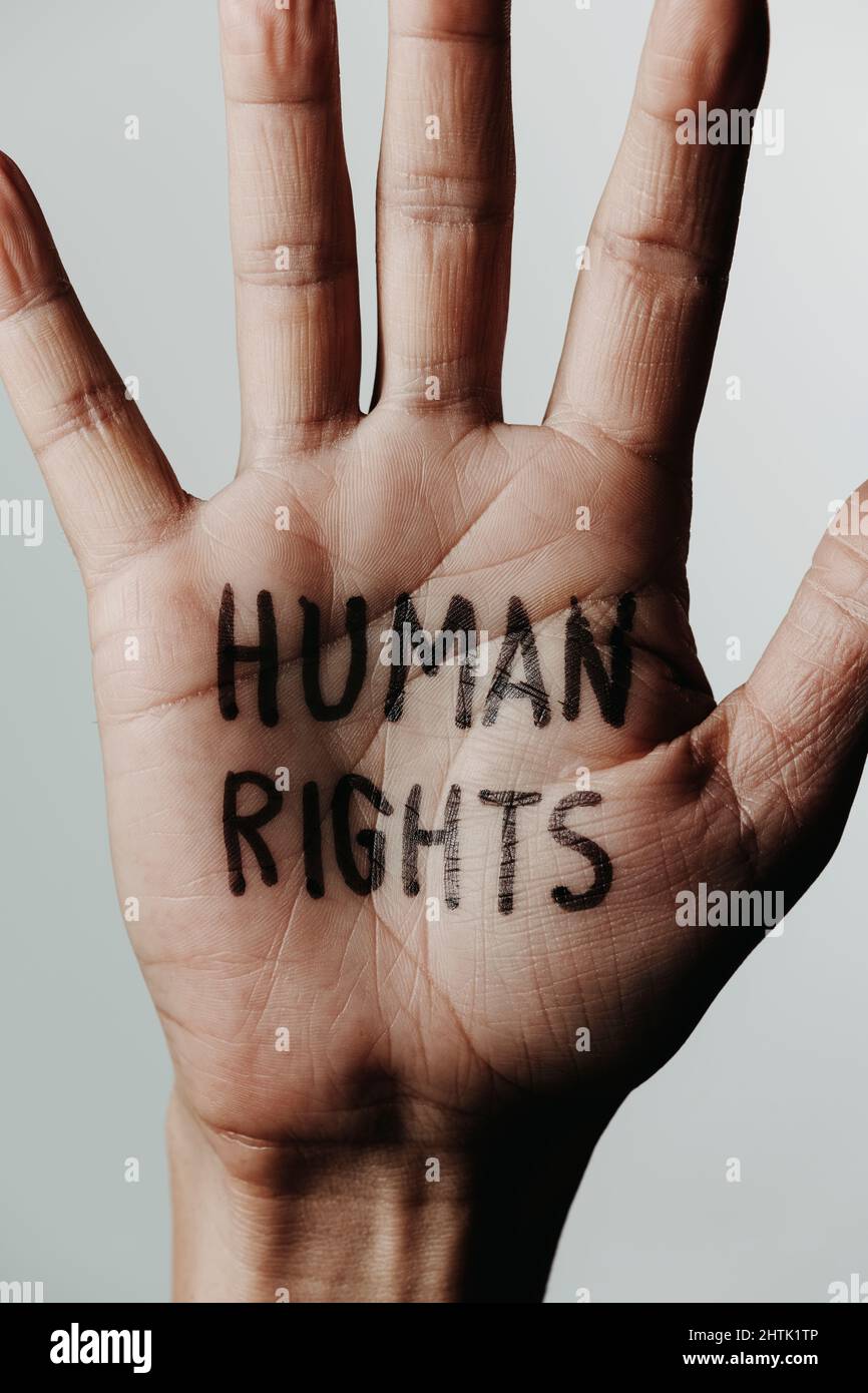 Nahaufnahme der Hand eines Mannes mit dem Text Menschenrechte in seiner Handfläche, auf einem cremefarbenen Hintergrund Stockfoto