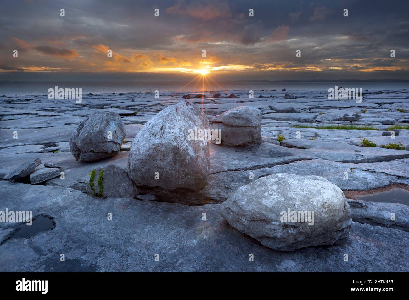 Typische Landschaft mit zerklüfteten Kalksteinpflaster und runden Felsbrocken bei Sonnenuntergang, The Burren, County Clare, Irland Stockfoto