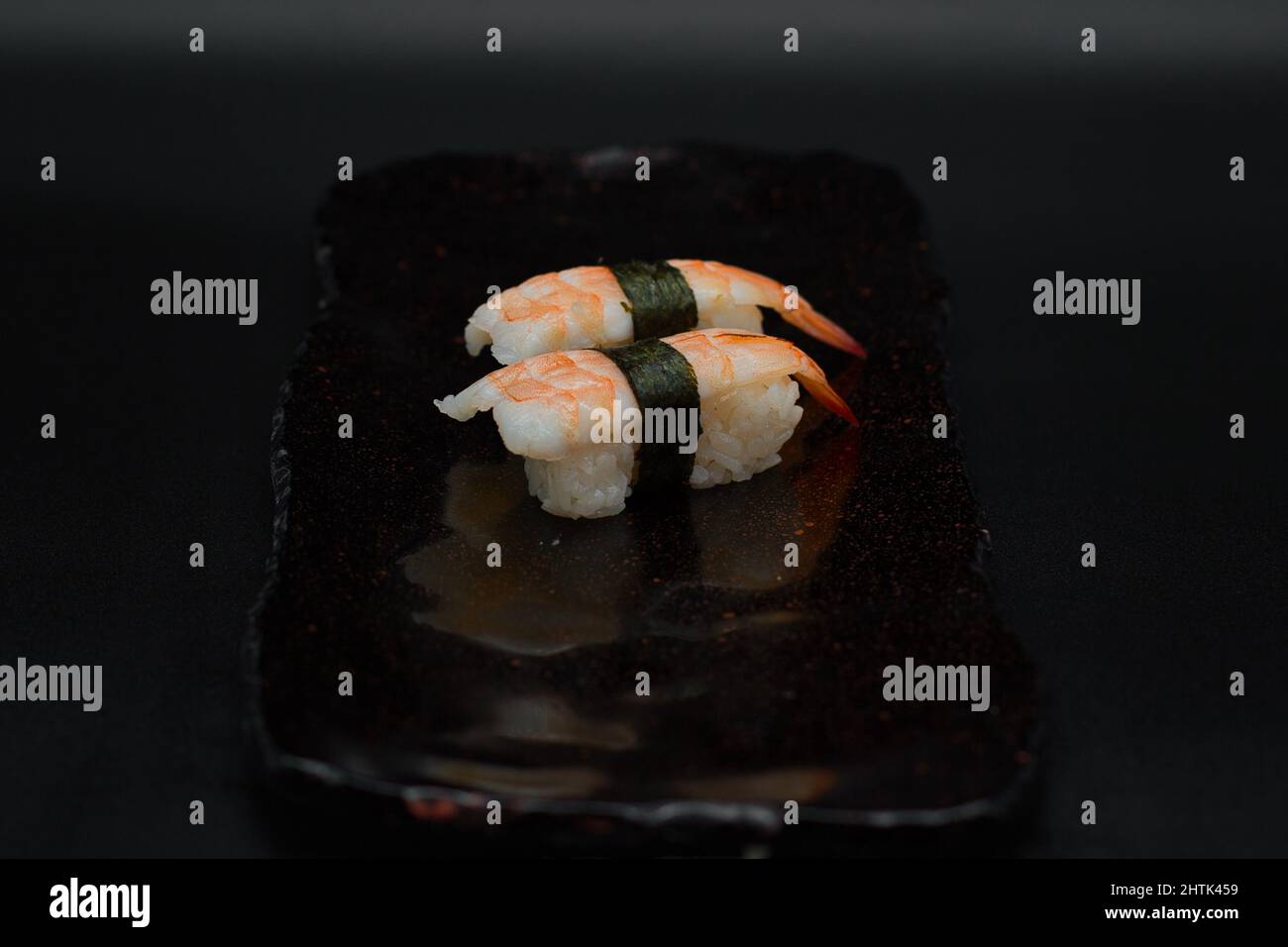 Zwei Einheiten Ebi King Premium Garnelen Nigiris, serviert auf schwarzem Teller auf schwarzem Hintergrund von einem japanischen Restaurantkoch. Stockfoto