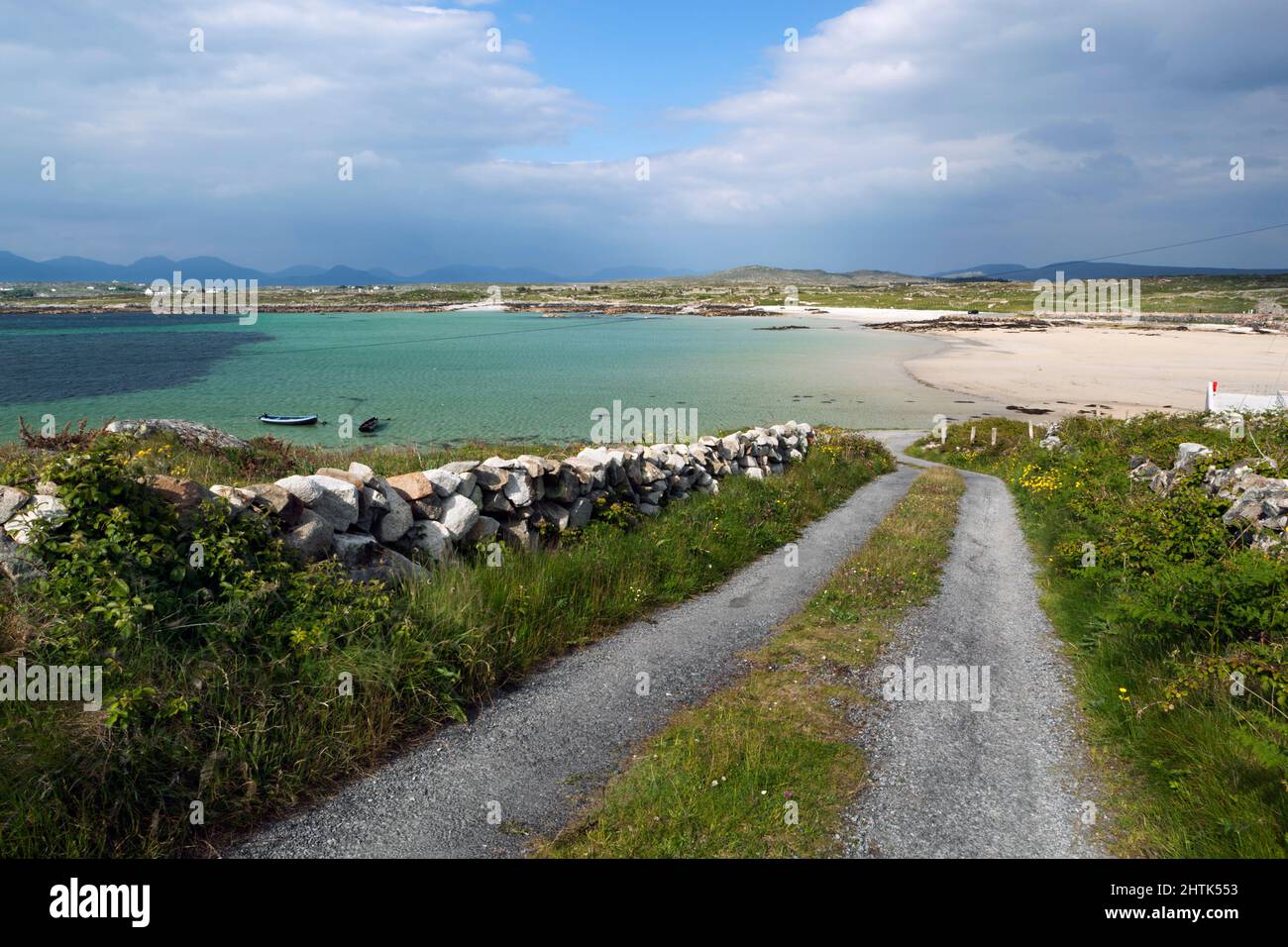 Die Landstraße führt hinunter zu einem abgelegenen Strand mit Bergen des Connemara National Park in der Nähe von Cashel, County Galway, Irland Stockfoto