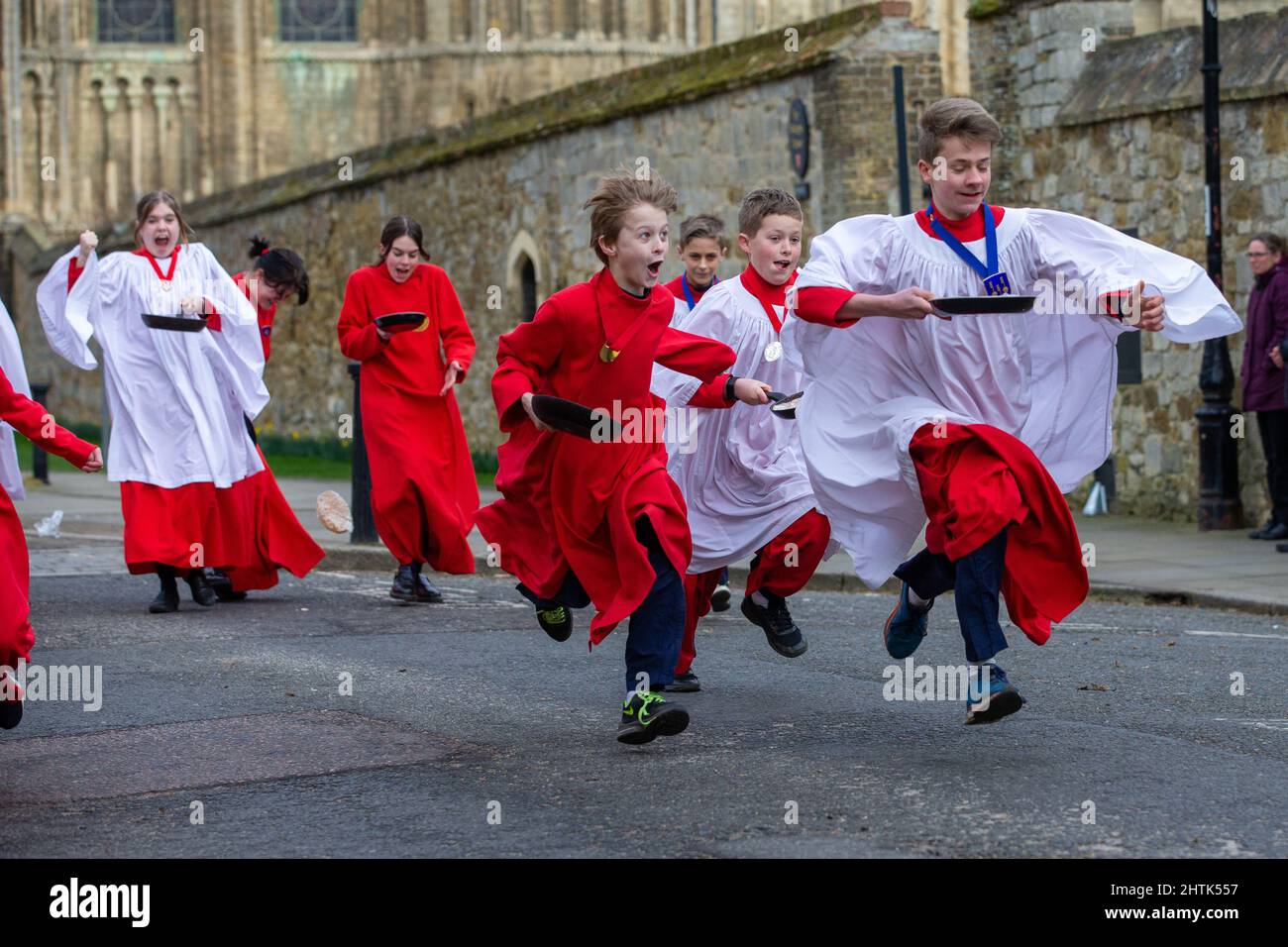 Bild vom 28.. Februar zeigt Choristers von Ely Cathedral in Cambridgeshire, die einen Übungslauf für das Shrove Tuesday Pancake Race machen. Choristers in Ely Cathedral in Cambridgeshire übten heute Morgen (Mo) für ihr jährliches Pfannkuchen-Rennen. Die 10 Jungen und Mädchen trugen ihre rot-weißen Soutanen, als sie Pfannkuchen vor der Kathedrale aus dem 12.. Jahrhundert drehten. Die Jugendlichen lachten und kicherten, als sie für die traditionelle Veranstaltung von morgen probten und versuchten, ihre Fähigkeiten beim Pfannkuchenwerfen zu verbessern. Jedes Jahr rast nach Evensong rund 20 Chorknaben das Kirchenschiff der Kathedrale entlang. Es ist das dritte l Stockfoto