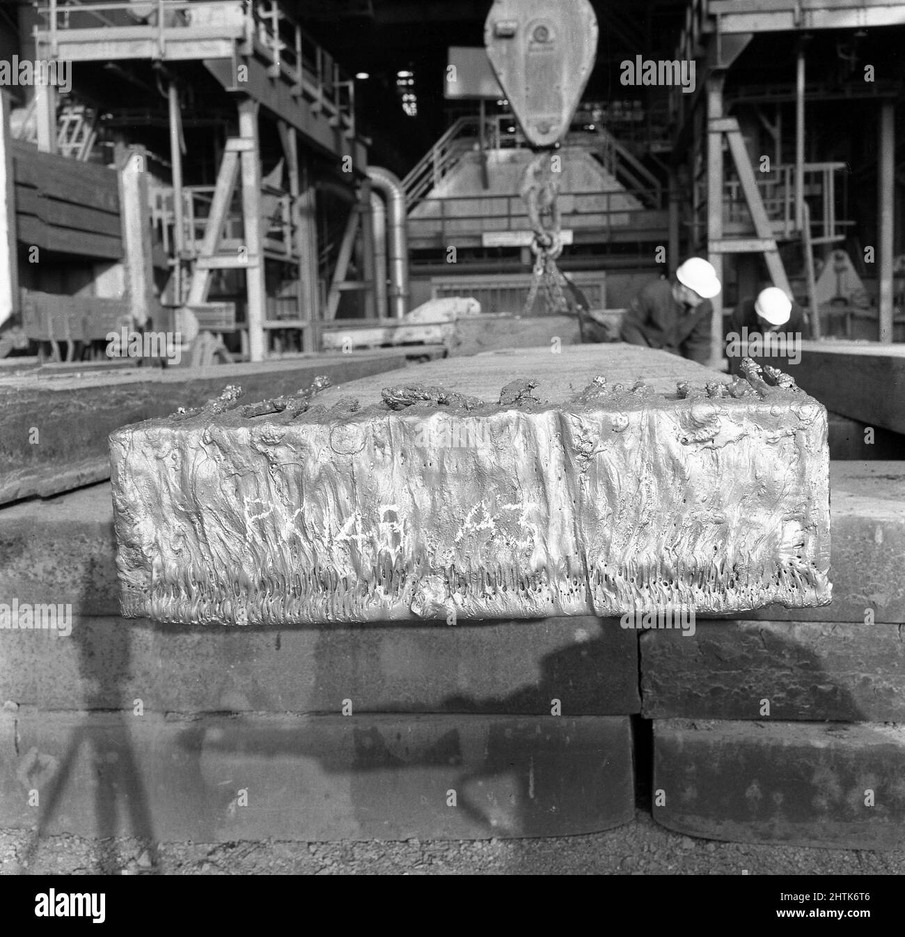 1950s, historisch, eine rechteckige Stahlplatte, mit Markierungen, in einer Slabing-Mühle in der Abbey Steel Works, Port Talbot, Glamorgan, Wales, Großbritannien. Traditionell hergestellt durch einen Hochofen, sind Platten halbfertige Metallblöcke, die für die Herstellung von "flachen" Stahlprodukten wie Blechen, Platten und anderem flachgewalztem Stahl verwendet werden. Stockfoto