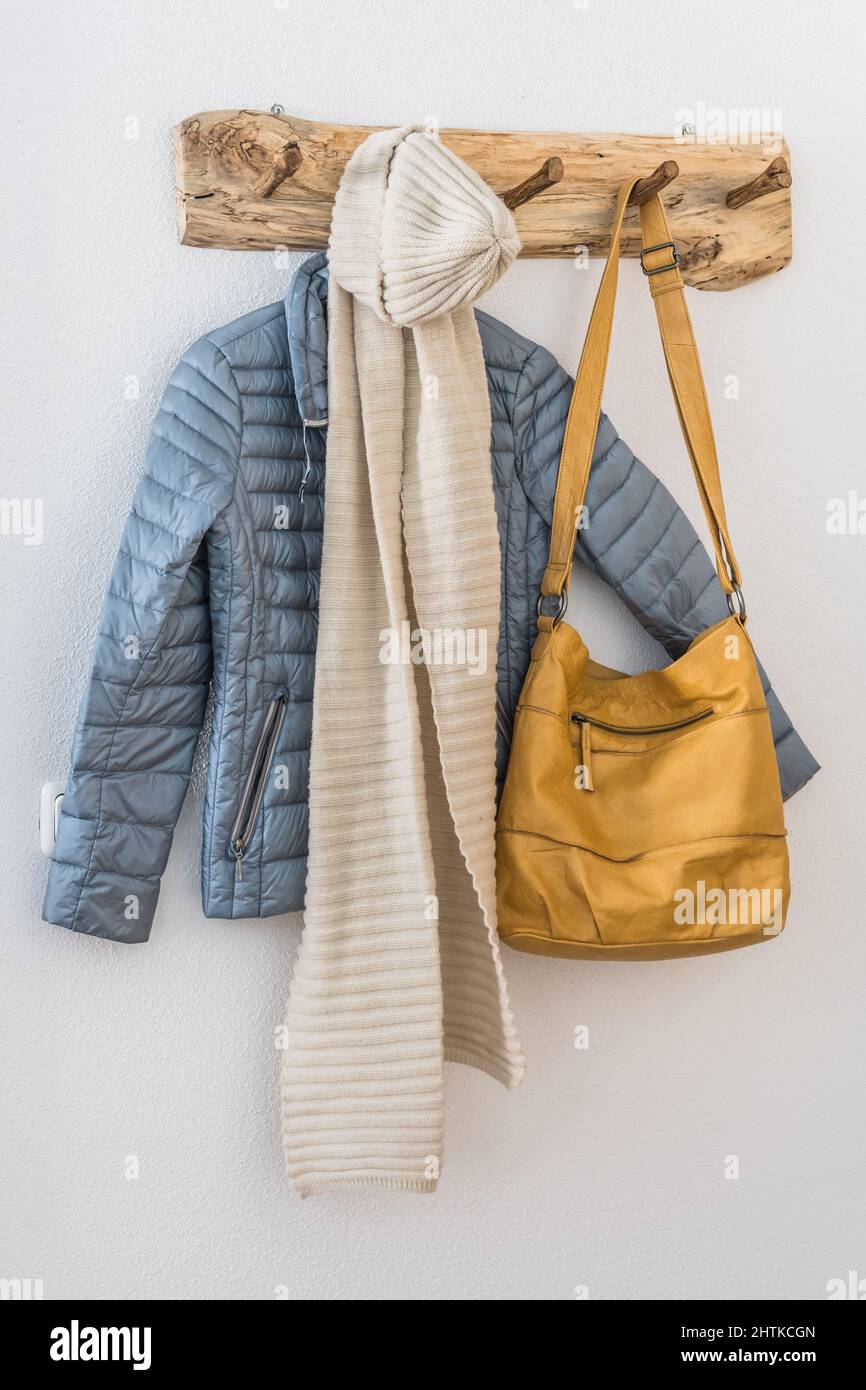 Naturholzmantel mit Jacke, Schal und Tasche an einer weißen Wand. Skandinavische Einrichtung. Stockfoto