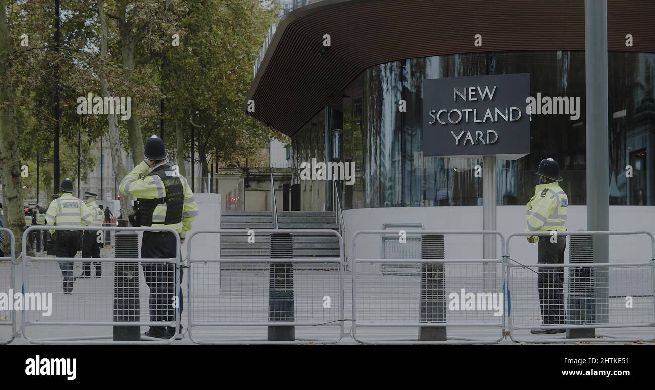 London, Großbritannien - 11 20 2021: Polizeibeamte mit Gesichtsmasken vor dem Gebäude des Hauptquartiers von New Scotland Yard am Victoria Embankment. Stockfoto