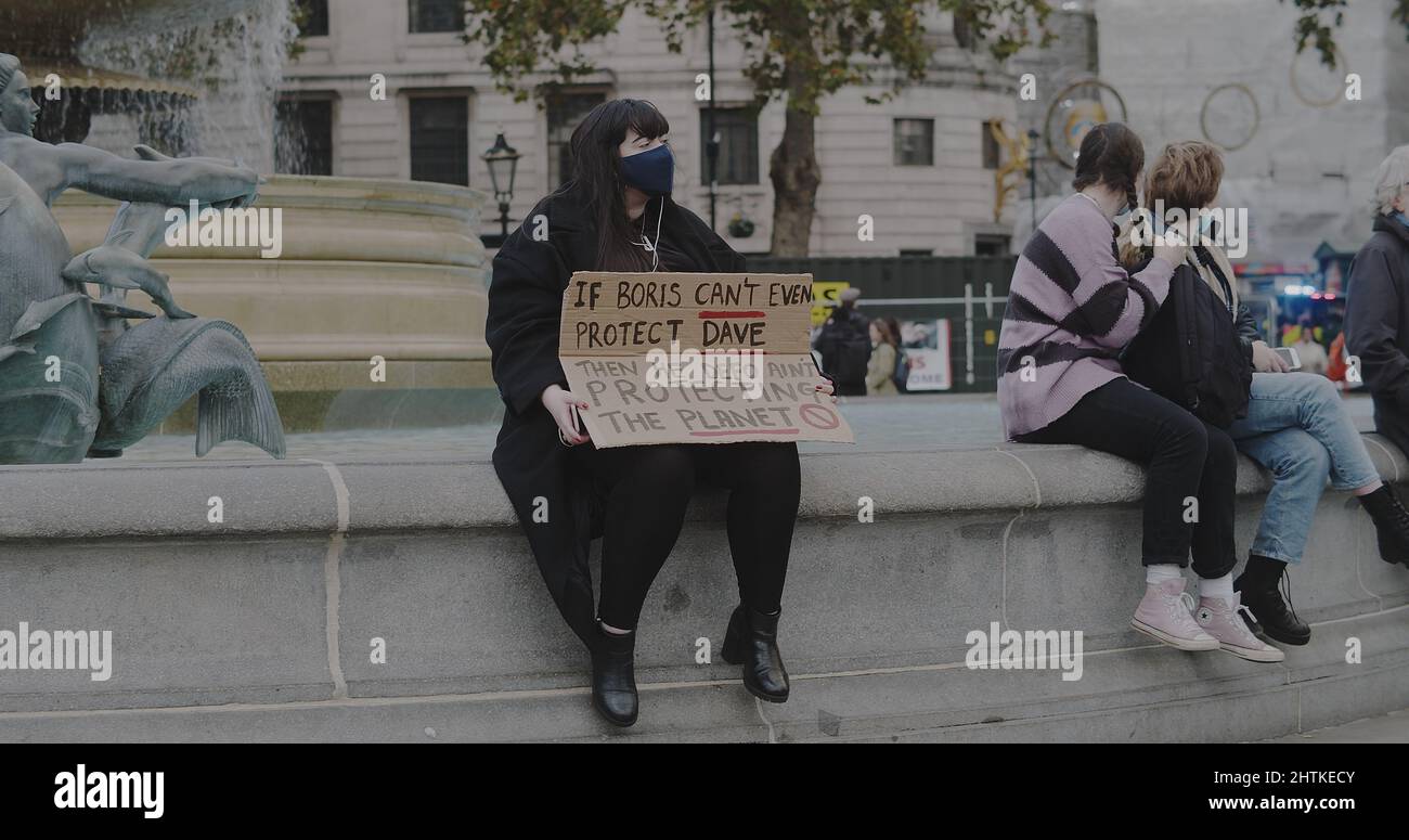 London, Großbritannien - 11 06 2021: Protestler, der eine Gesichtsmaske trägt und ein Schild am Trafalgar Square in London hält, für COP26. Stockfoto
