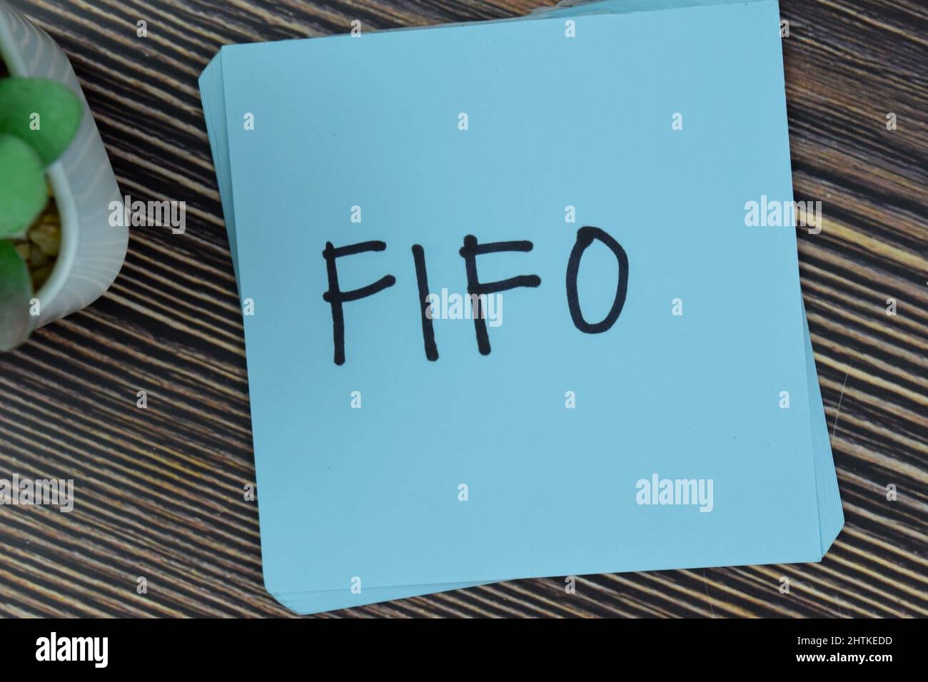 FIFO schreibt auf Haftnotizen isoliert auf Holztisch. Stockfoto