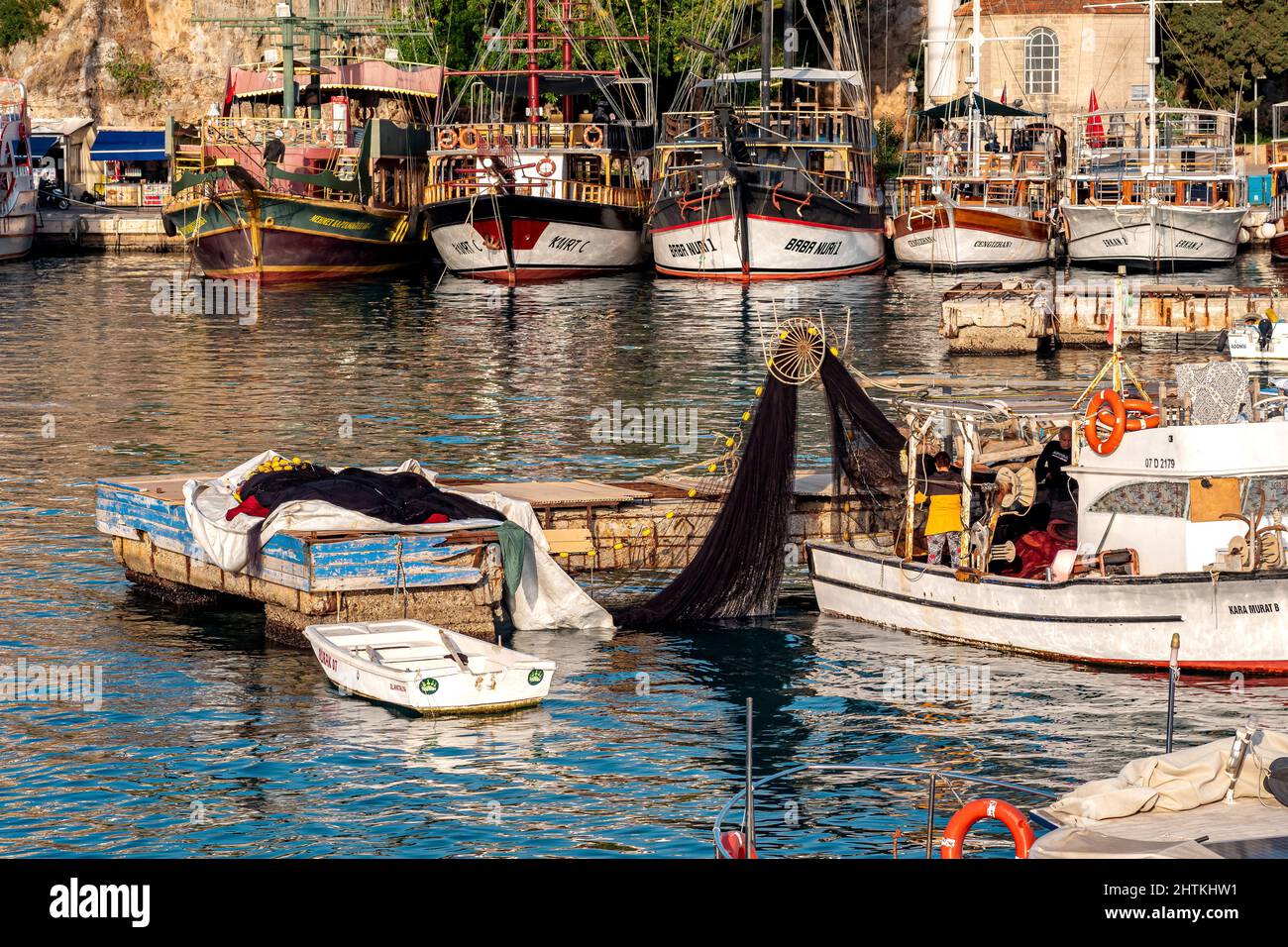 Antalya, Türkei - 17. November 2021: Fischer überprüfen die Netze auf einem Fischerboot vor dem Hintergrund von Freizeitschiffen im Vintage-Stil in der A Stockfoto