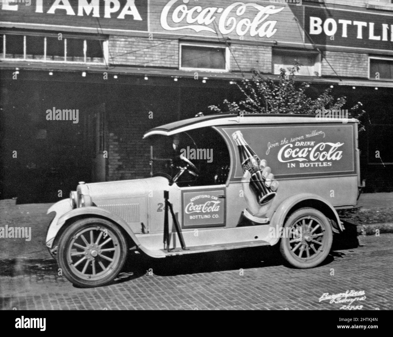 Coca Cola im Jahr 1920s. Ein Auto mit Werbung für Coca Cola steht auf der Straße. Stockfoto