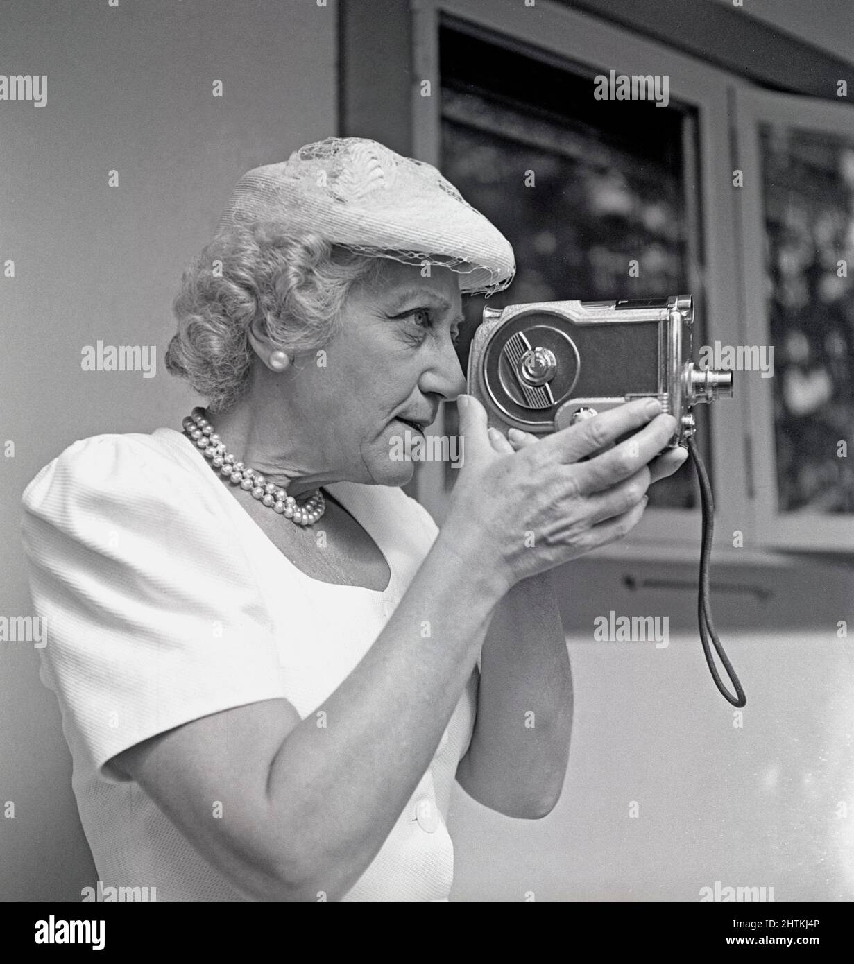 Amateur Dreharbeiten in der 1940s. Eine ältere Frau benutzt eine Filmkamera, hält sie und zielt sie auf etwas. Ein Amateurgerät, um Filme zu Filmen, um sie zu Hause anzusehen. Schweden 1948 Kristoffersson Ref. AL31-3 Stockfoto