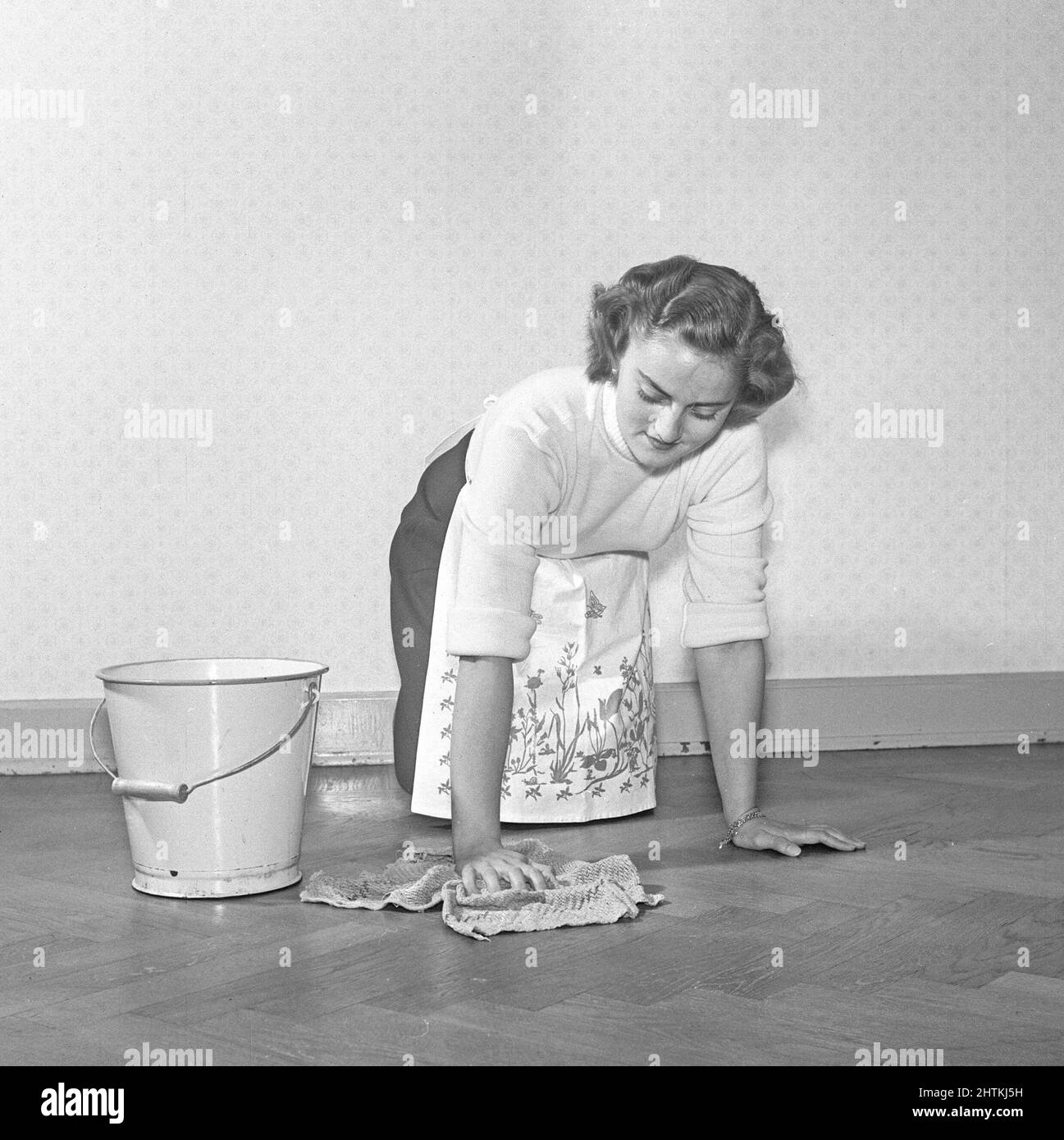 Reinigen des Bodens damals. Eine junge Frau liegt auf dem Boden und verwendet eine Scheuerbürste, um den Boden sauber zu machen. Schweden 1952 Kristoffersson Ref. BD49-8 Stockfoto