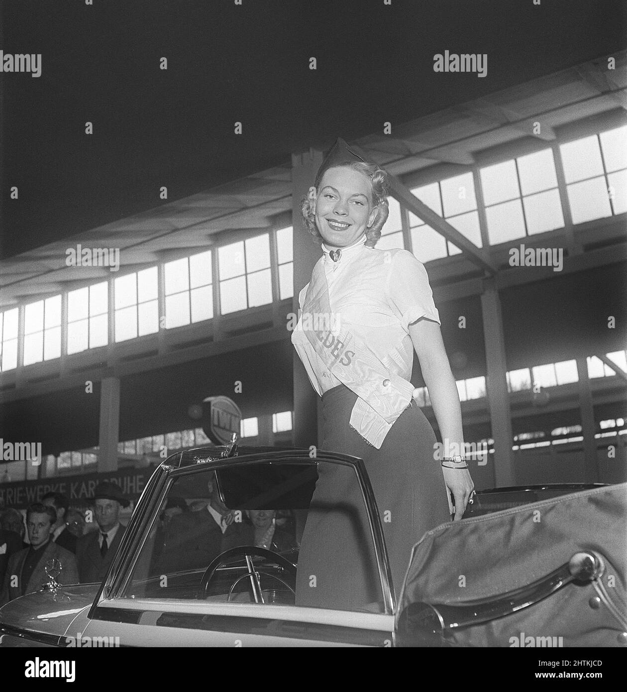 In der 1950s. Eine junge Frau, die im Mercedes-Bereich einer Messe arbeitet, steht in einem Mercedes-Benz Modell 170 S, einem zweisitzigen Cabriolet. Sie hat ein Banner mit dem Namen Mercedes auf sich. Schweden 1951 Kristoffersson Ref. BD38-6 Stockfoto