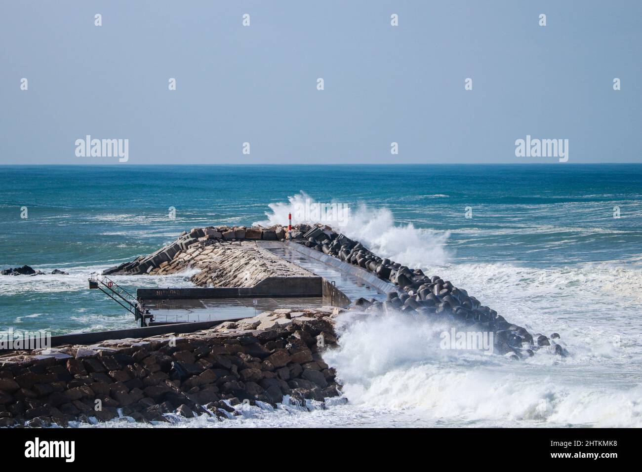 An einem stürmischen Tag traf von einem Pier aus eine große Meereswelle in einem Steg ein Stockfoto