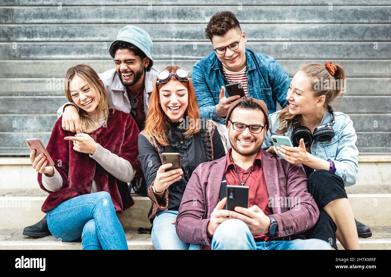 Multikulturelle urbane Freunde, die am städtischen Ort Spaß am Handy haben - Junge glückliche Jungs und Mädchen, die sich gemeinsam Zeit nehmen und lustige Videos auf Smart ansehen Stockfoto