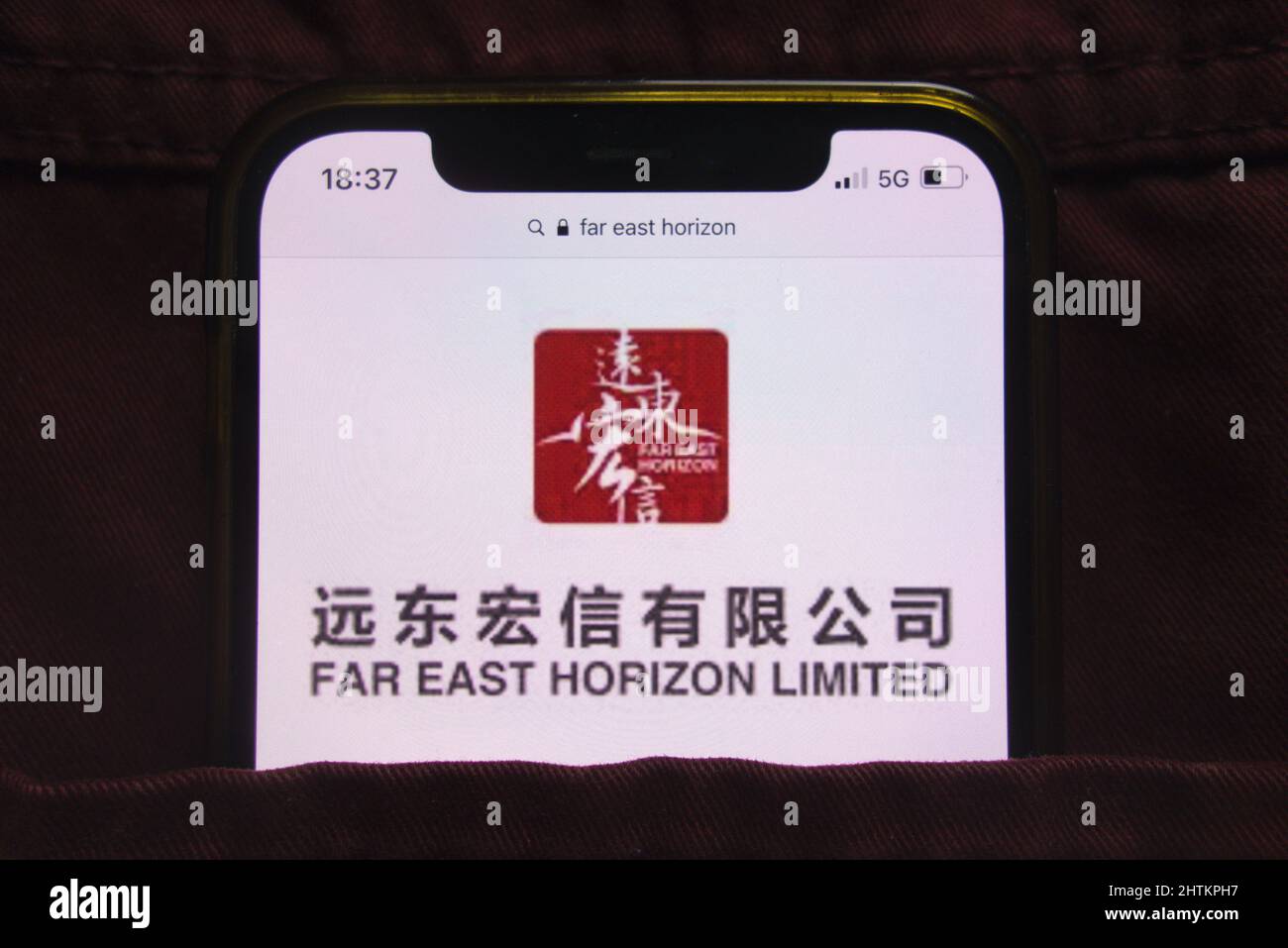 KONSKIE, POLEN - 27. Februar 2022: Far East Horizon Limited-Logo auf dem Mobiltelefon, versteckt in der Jeans-Tasche Stockfoto