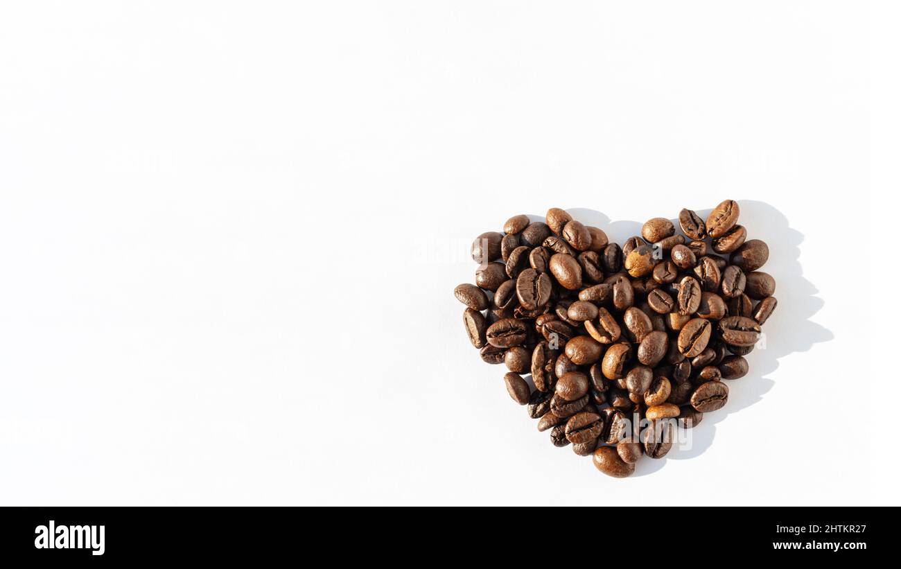 Herzform von Robusta, Arabica-Kaffeebohnen isoliert auf weißem Hintergrund, Banner, Kopierbereich. Kaffeebohnen für Latte, Cappuccino, Mokka, Americano CO Stockfoto