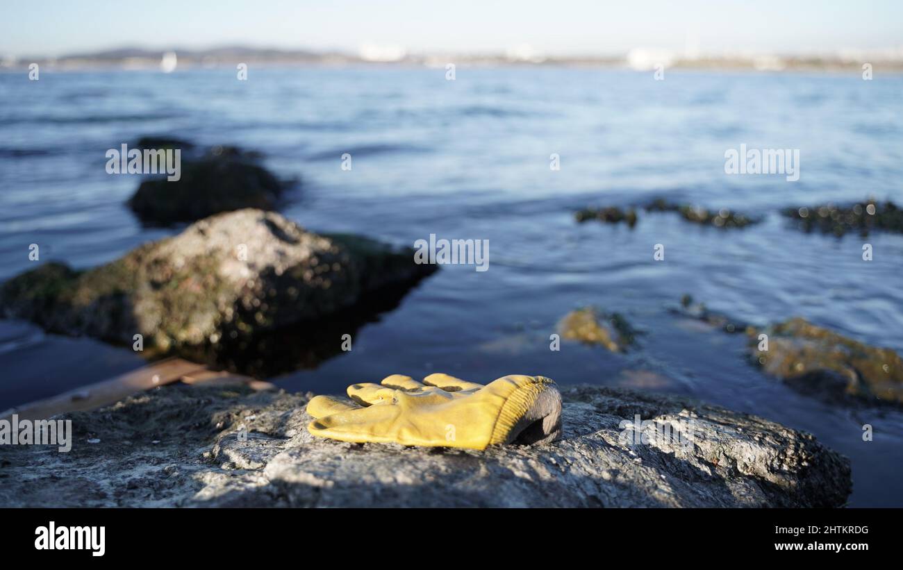 Plastikhandschuhe, die am Meer auf die Felsen geworfen werden Stockfoto