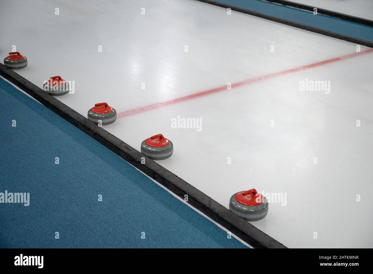 Anordnung von farbigem Curling Stone auf dem Eisplatz im Stadion des Curling Game Center Stockfoto