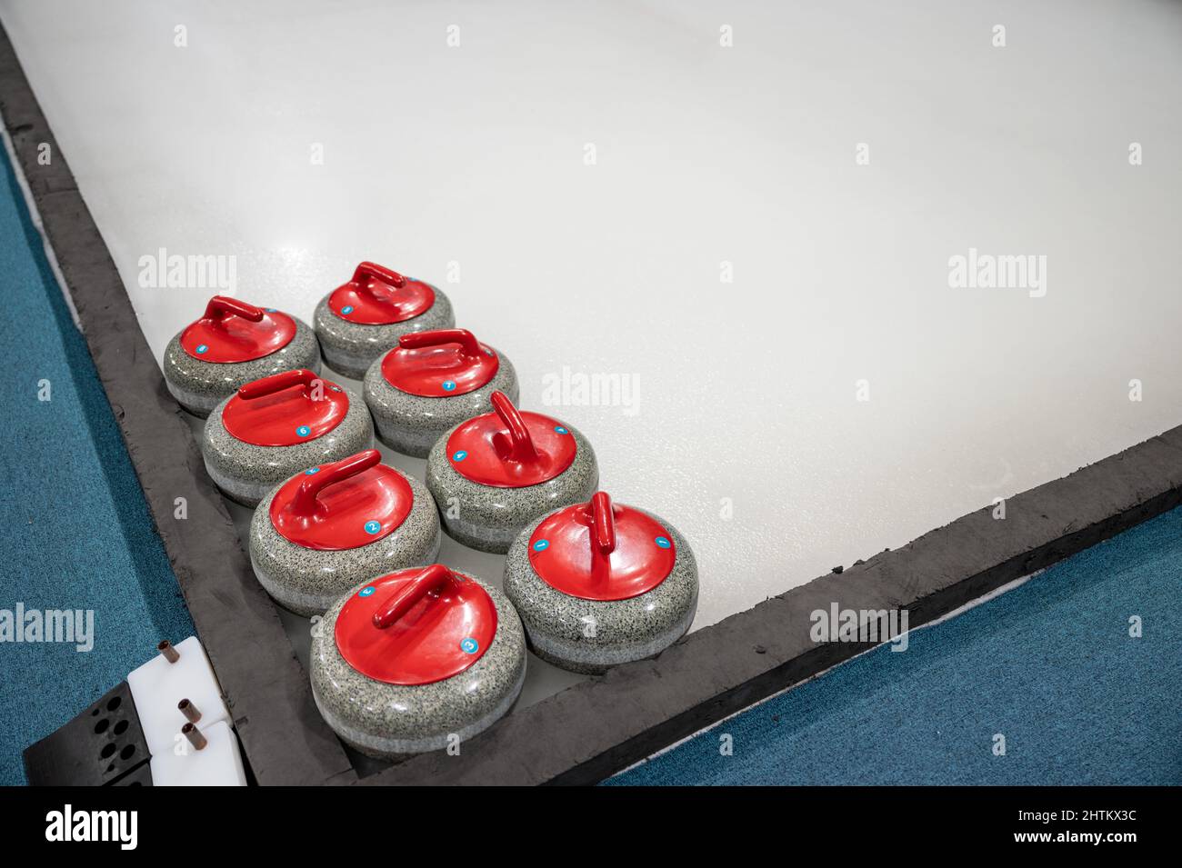 Anordnung von farbigem Curling Stone auf dem Eisplatz im Stadion des Curling Game Center Stockfoto