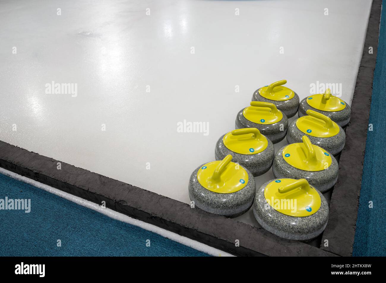 Anordnung von farbigem Curling Stone auf dem Eisplatz im Stadion des Curling Game Center Stockfoto