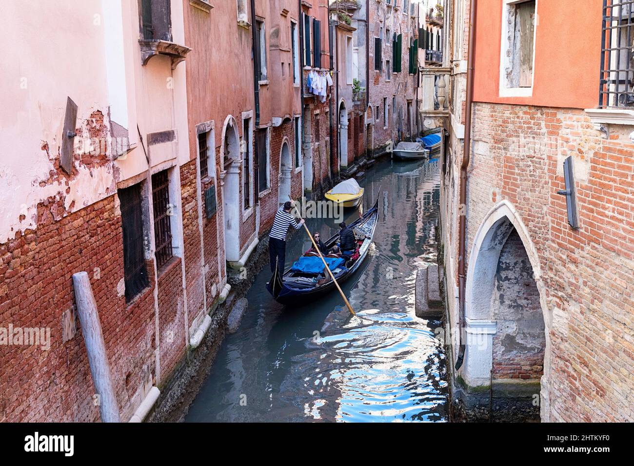 Touristen erkunden enge venezianische Kanäle mit traditionellen Gondeln, umgeben von historischen Gebäuden und klassischer venezianischer Architektur in Venedig, Italien Stockfoto