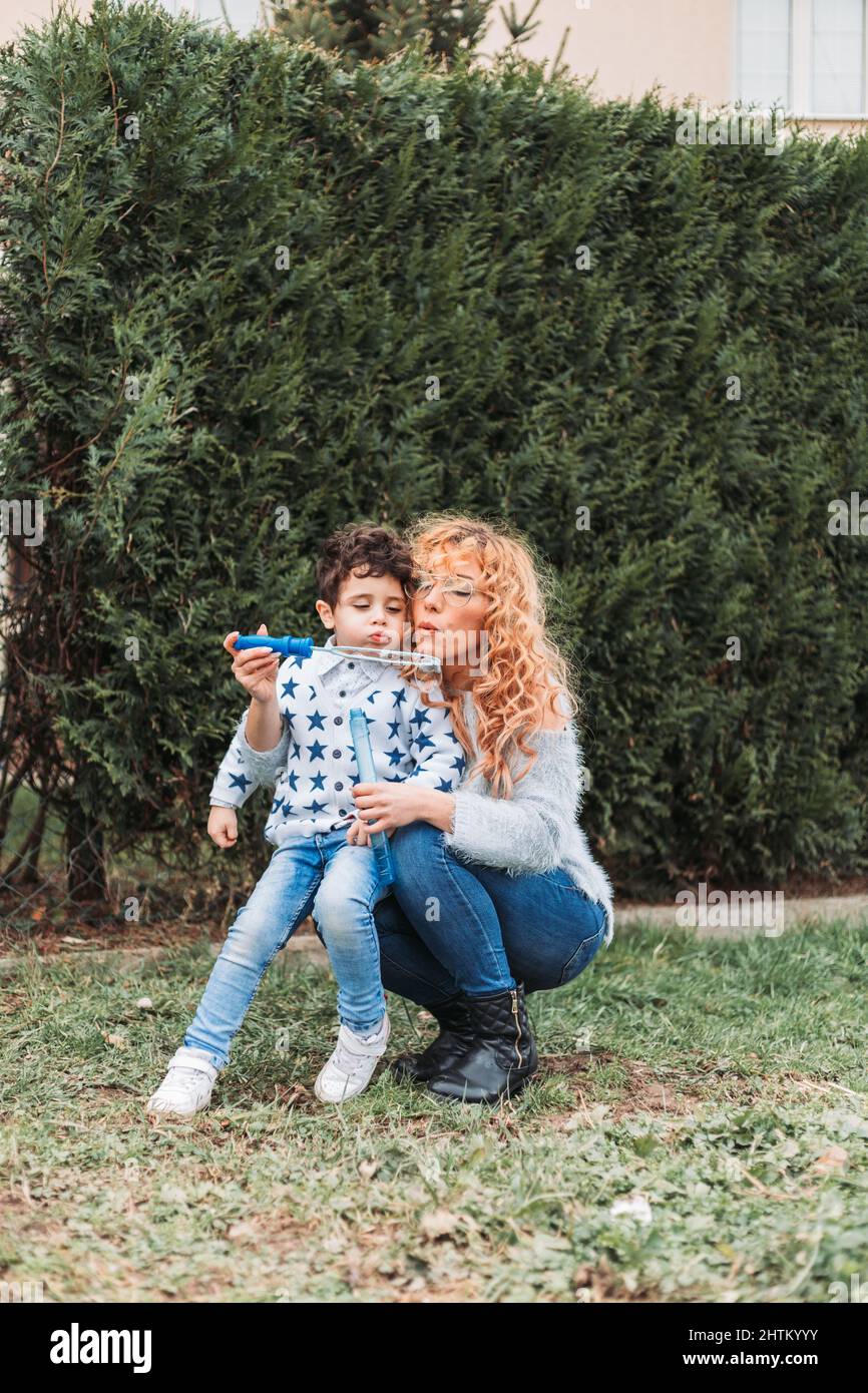 Mama spielt mit ihrem kleinen Jungen im Freien. Machen Seifenblasen mit Blasen kleben Stockfoto