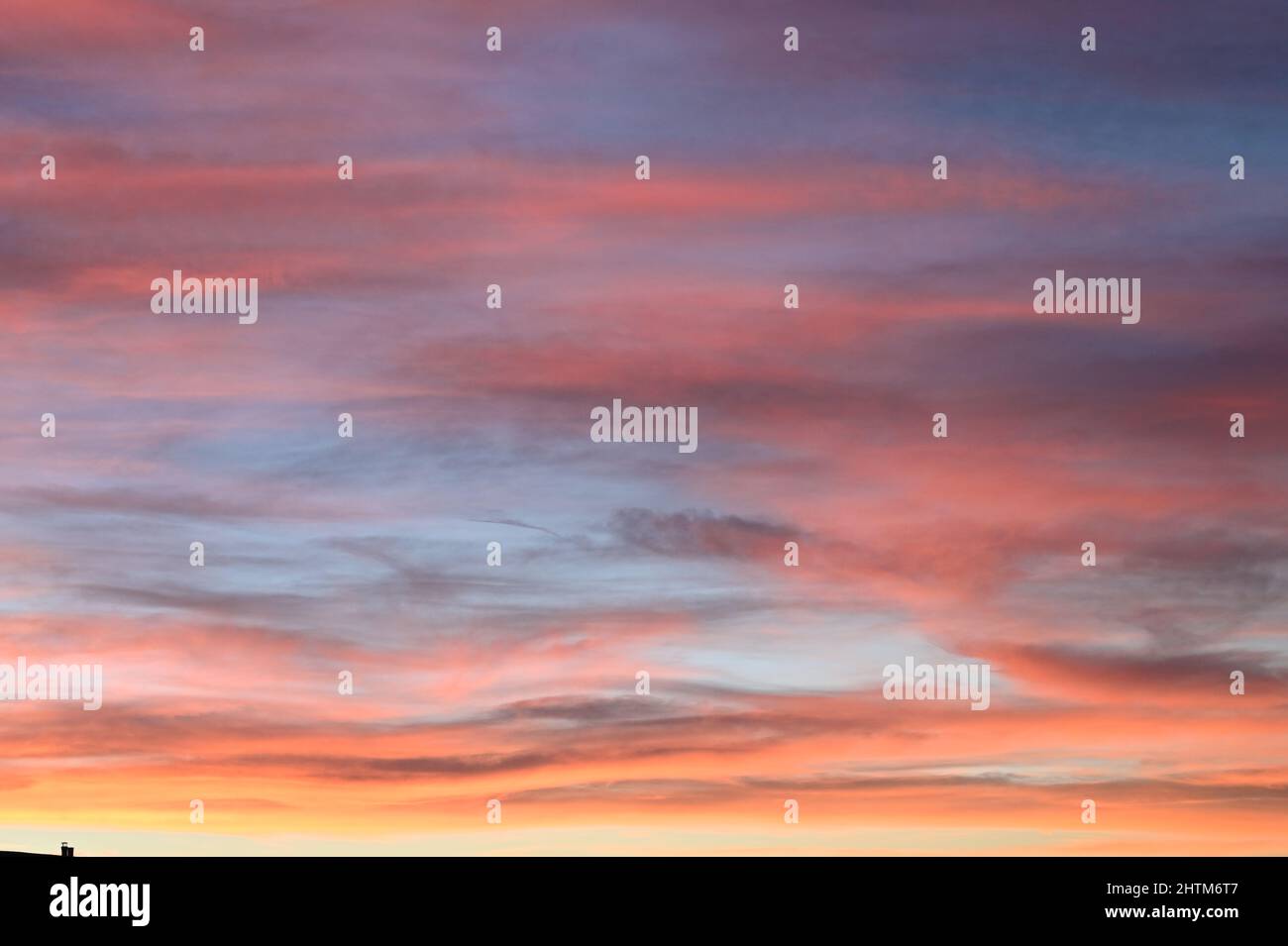 Ein wunderschöner Sonnenuntergang am Himmel, der das Rot, die Orangen, das Violett und das Blau der untergehenden Sonne hervorhebt Stockfoto